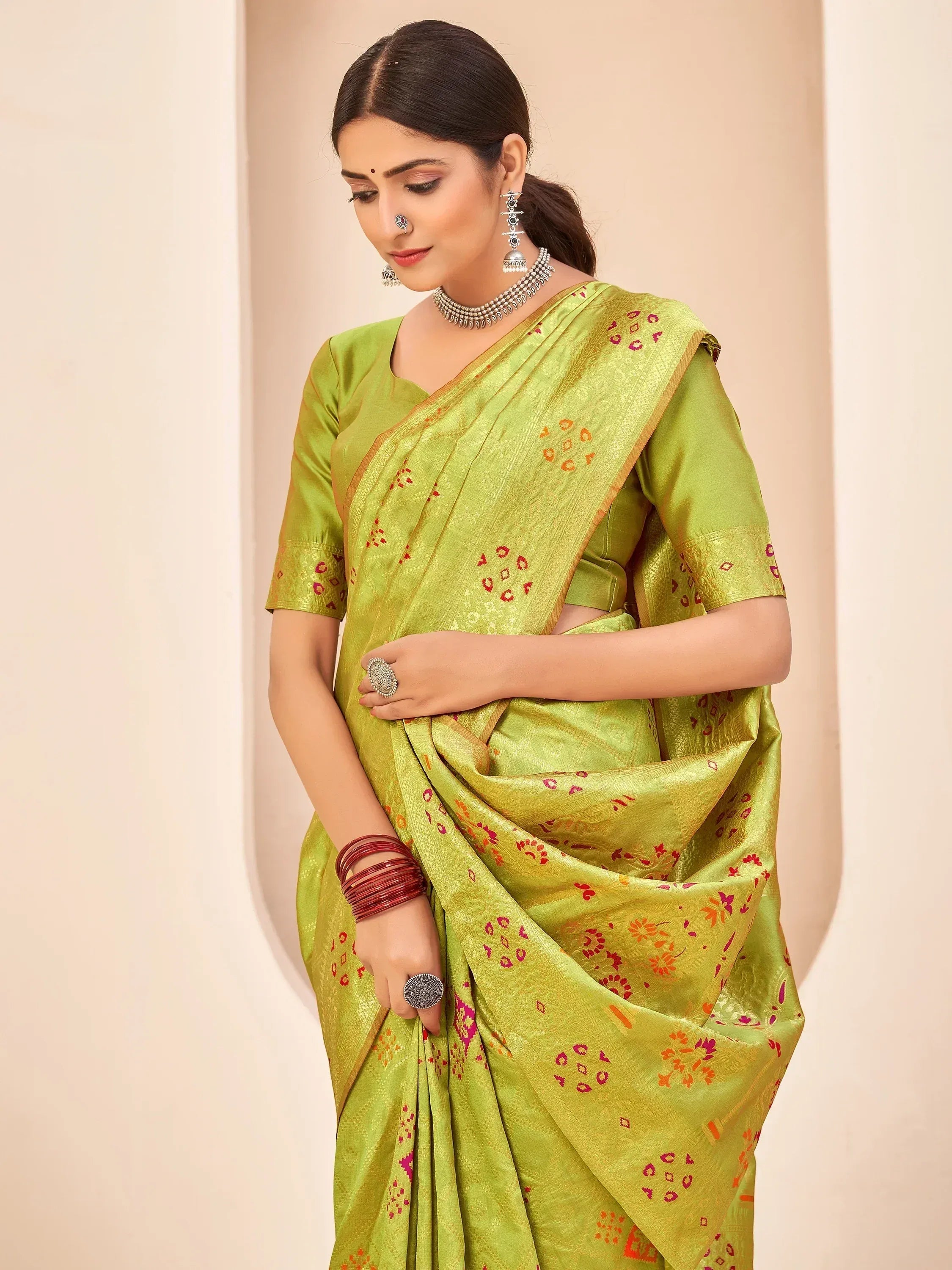 Lime green ethnic saree with floral motifs and gold border, paired with traditional jewelry