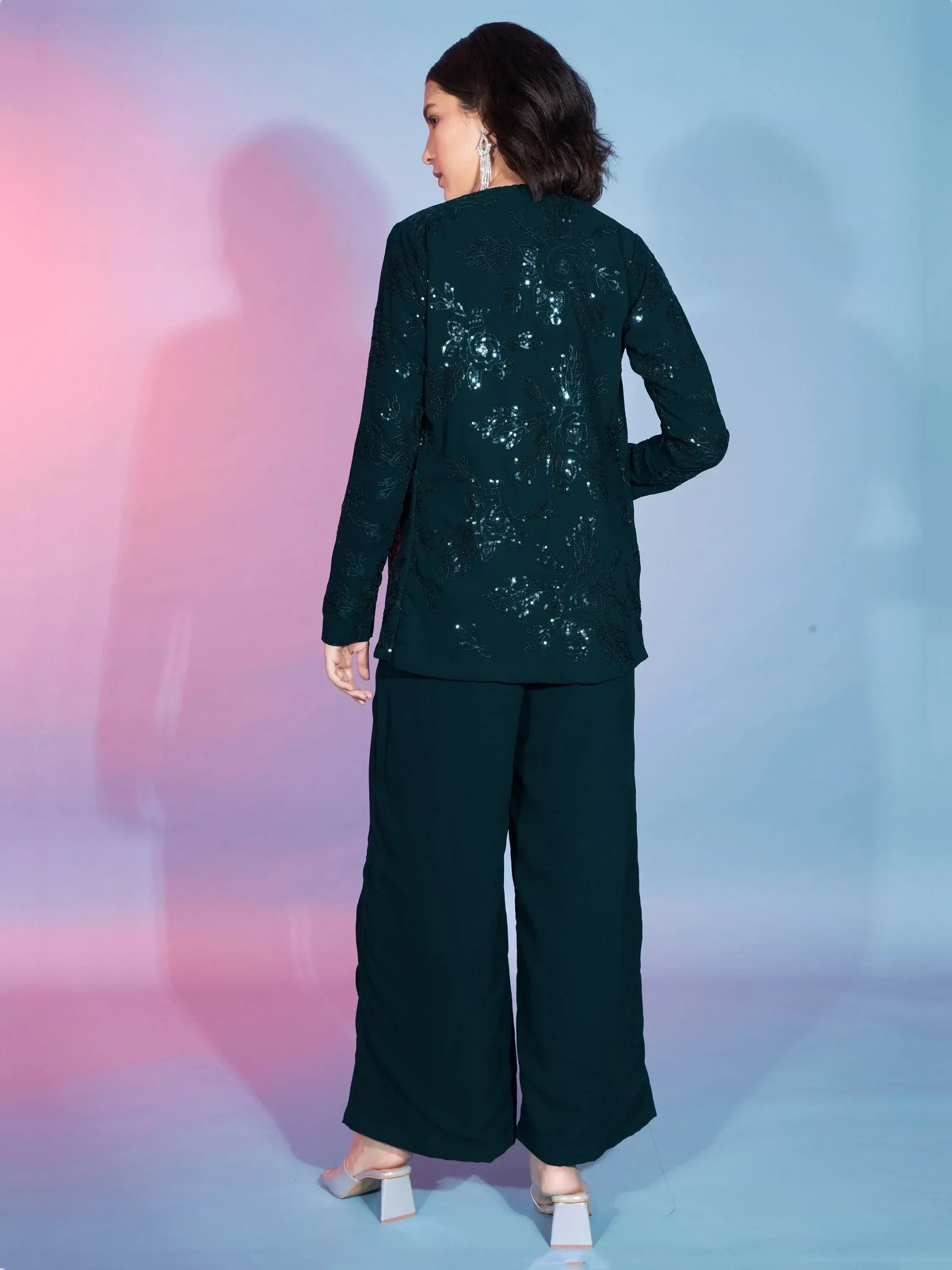 Emerald green ethnic suit with sequin floral embroidery, wide-leg pants, and statement earrings for festive occasions.