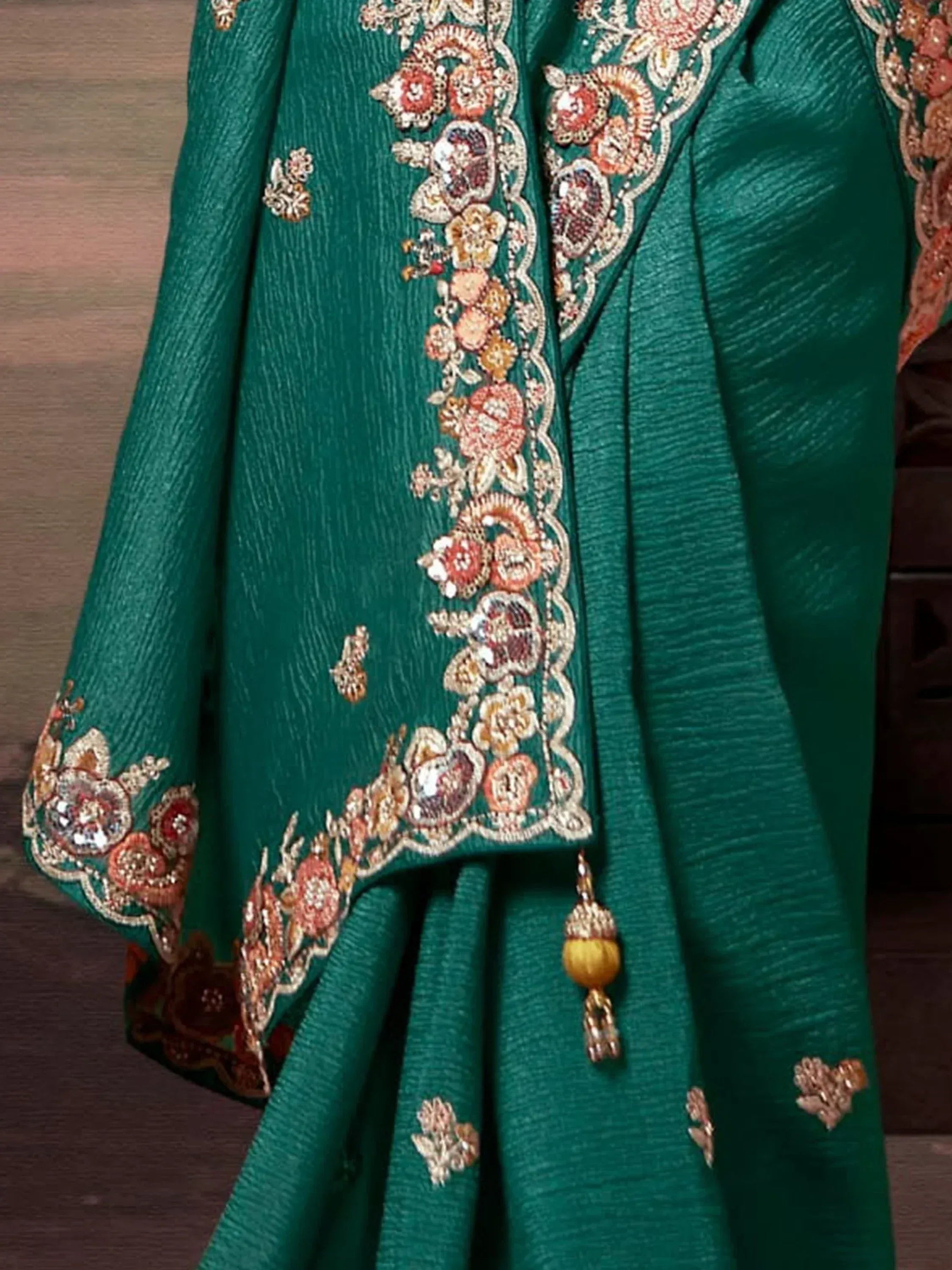 Emerald green ethnic gown with floral embroidery and tassels, perfect for Indian weddings and festive occasions.