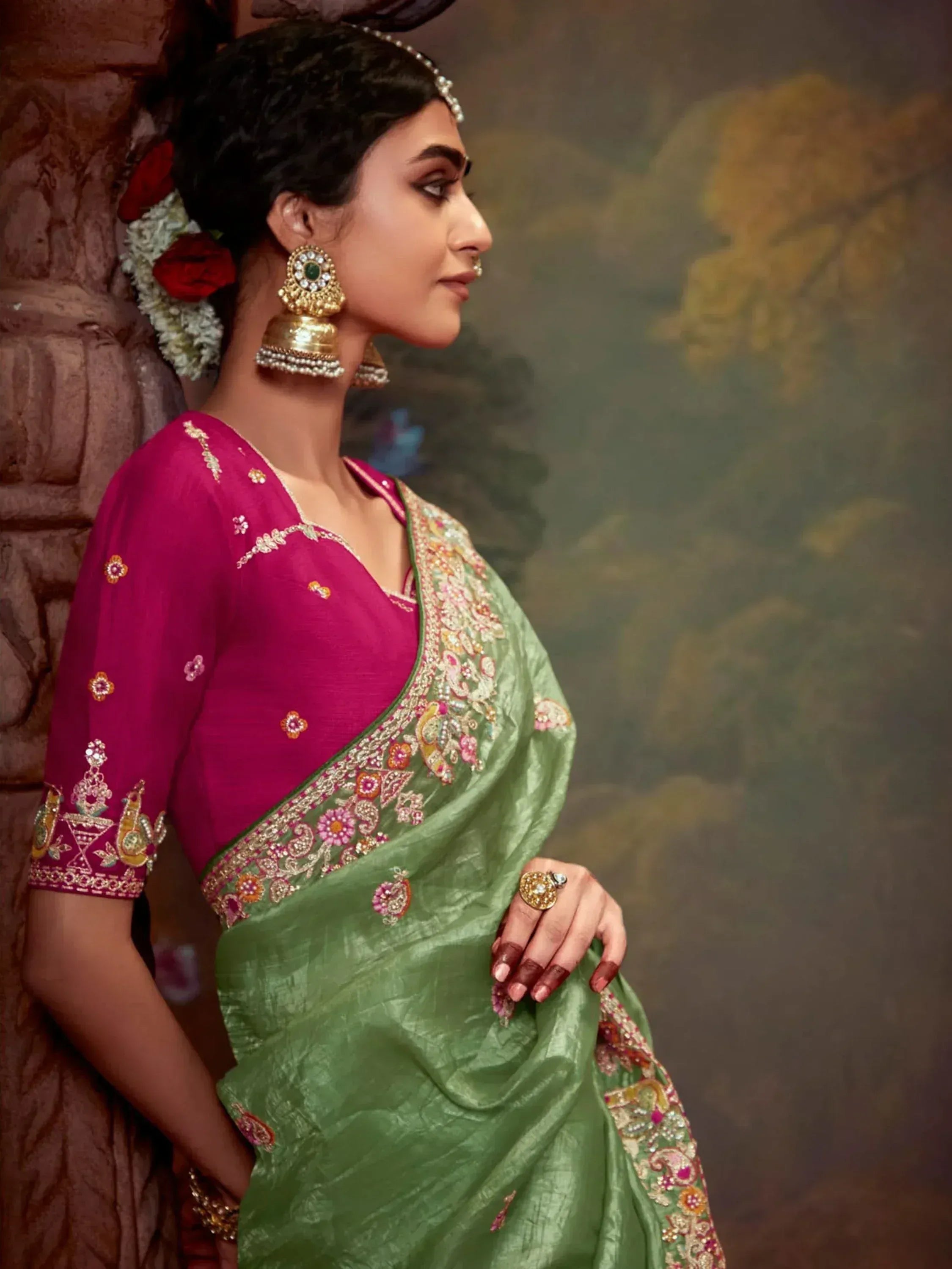 Woman in green embroidered saree with pink blouse, traditional Indian ethnic wear, floral jewelry