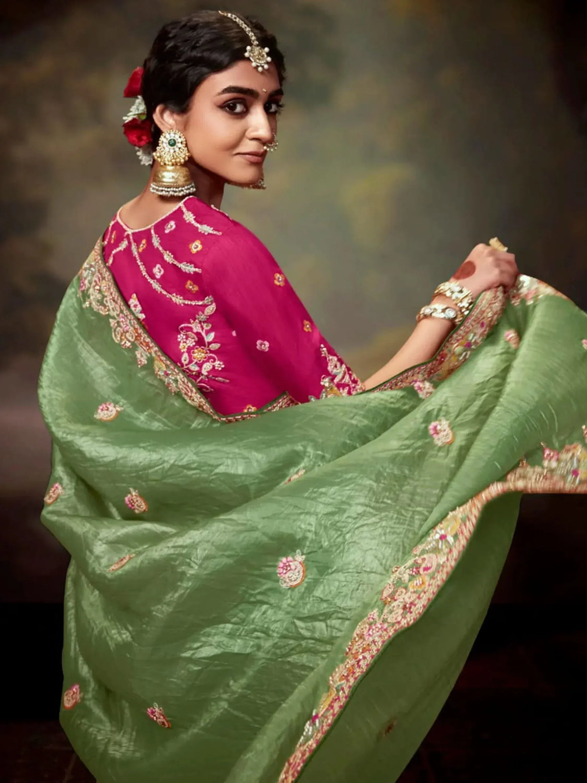 Woman in green embroidered saree with pink blouse, traditional Indian ethnic wear, floral jewelry