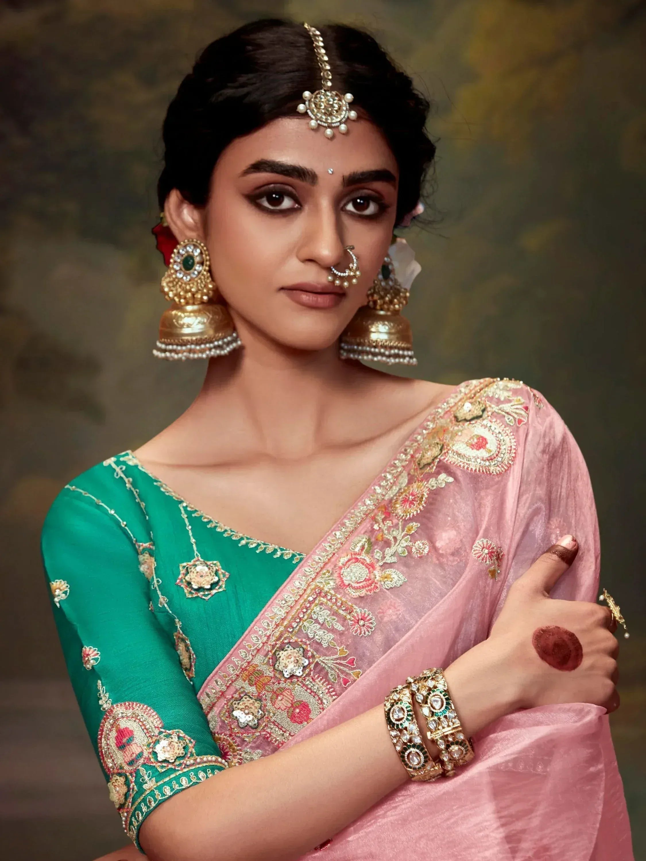 Woman in pink and green embroidered saree with gold jewelry, traditional Indian ethnic wear
