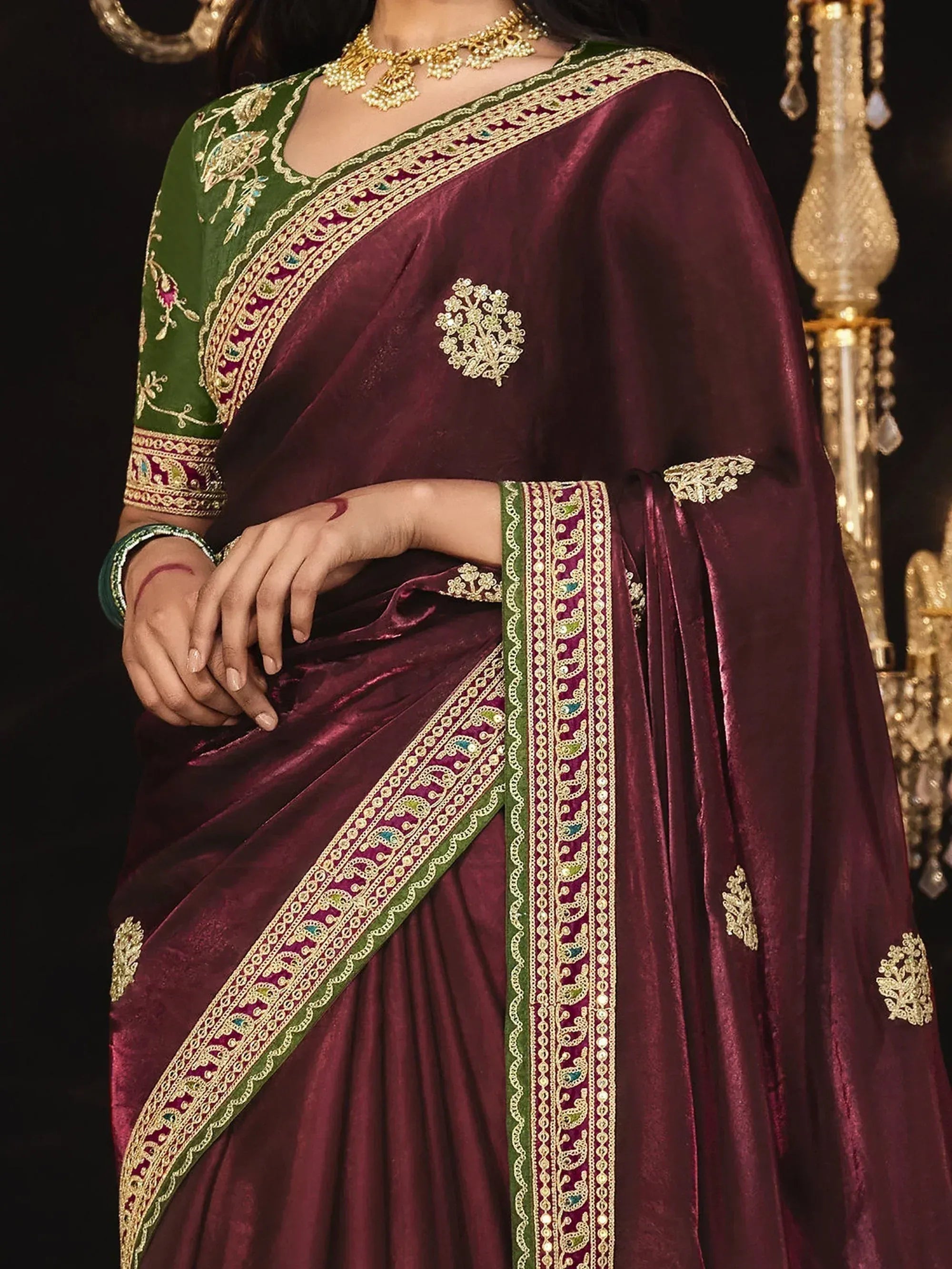Elegant maroon velvet saree with green blouse, gold embroidery, and intricate border design for Indian ethnic wear.