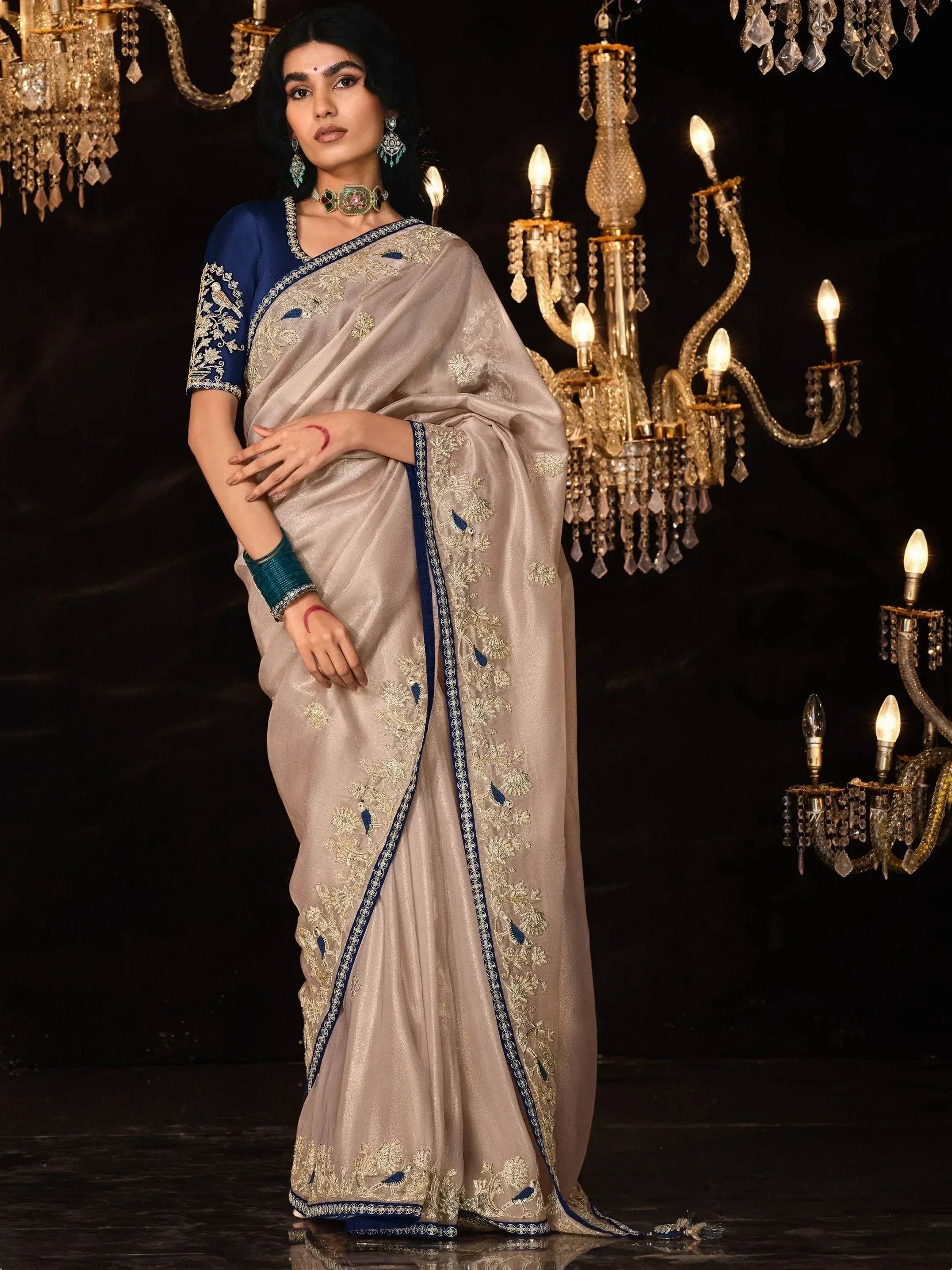 Elegant beige saree with blue and gold embroidery, paired with matching blouse, perfect for Indian ethnic wear occasions.