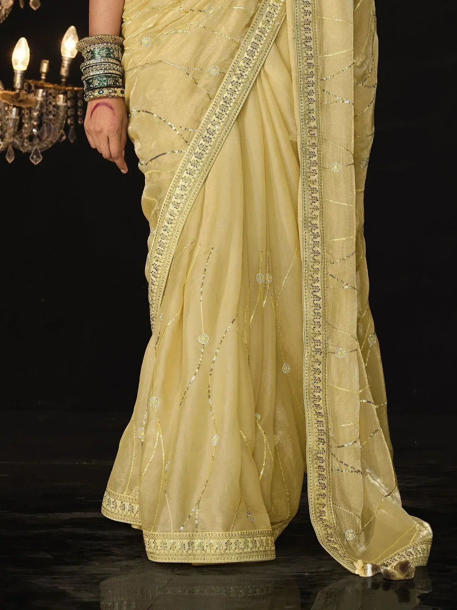 Elegant light yellow saree with gold embroidery and embellished border, styled with traditional bangles
