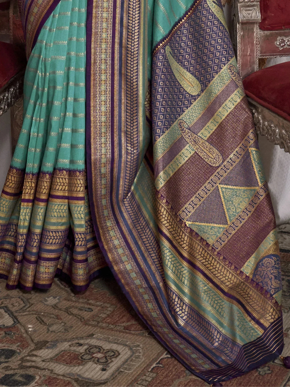 Teal and purple designer saree with intricate gold zari work, paisley motifs, and traditional border patterns.