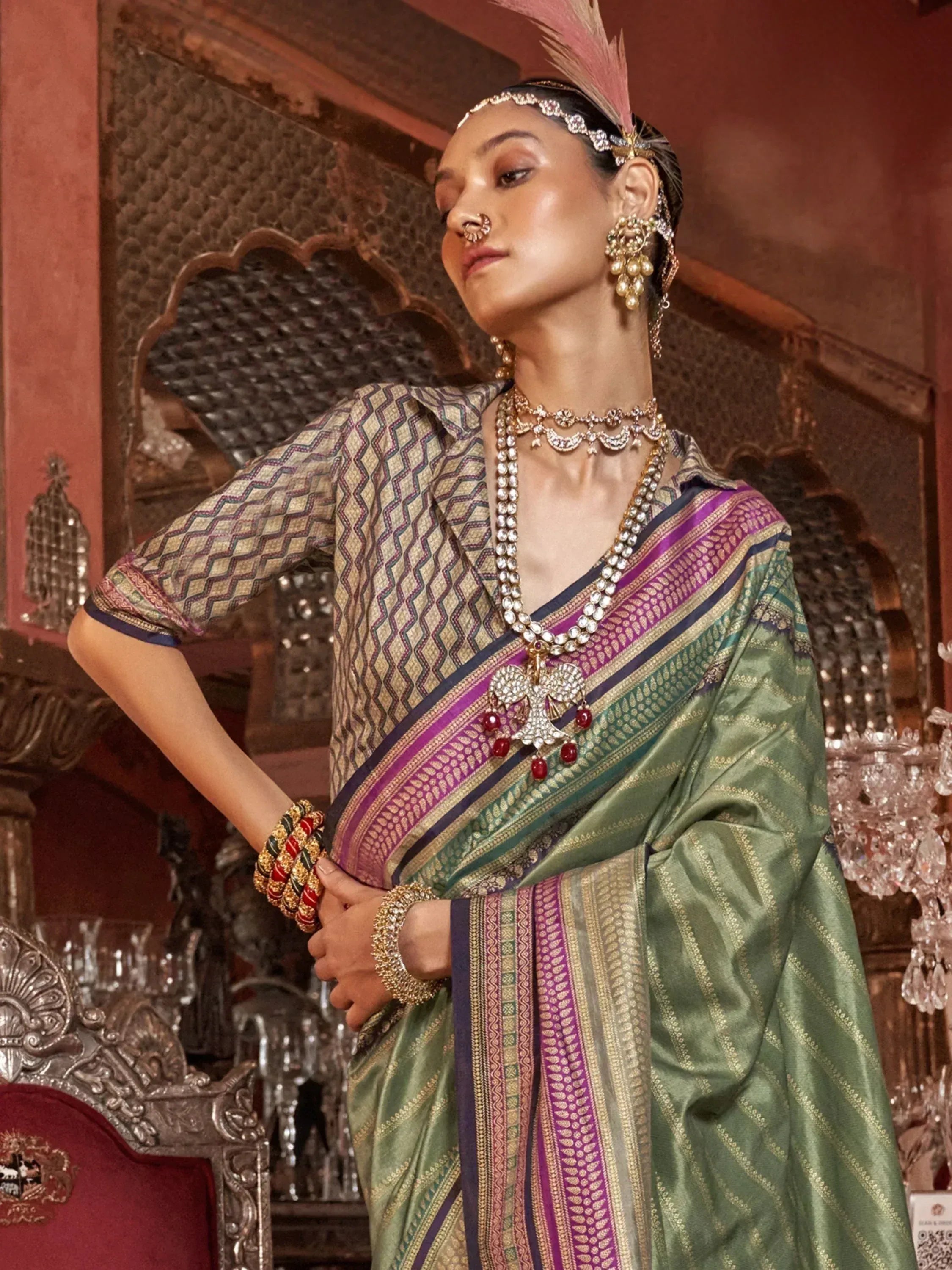 Elegant woman in green and purple Indian saree with intricate jewelry and feather headpiece, showcasing traditional ethnic wear.