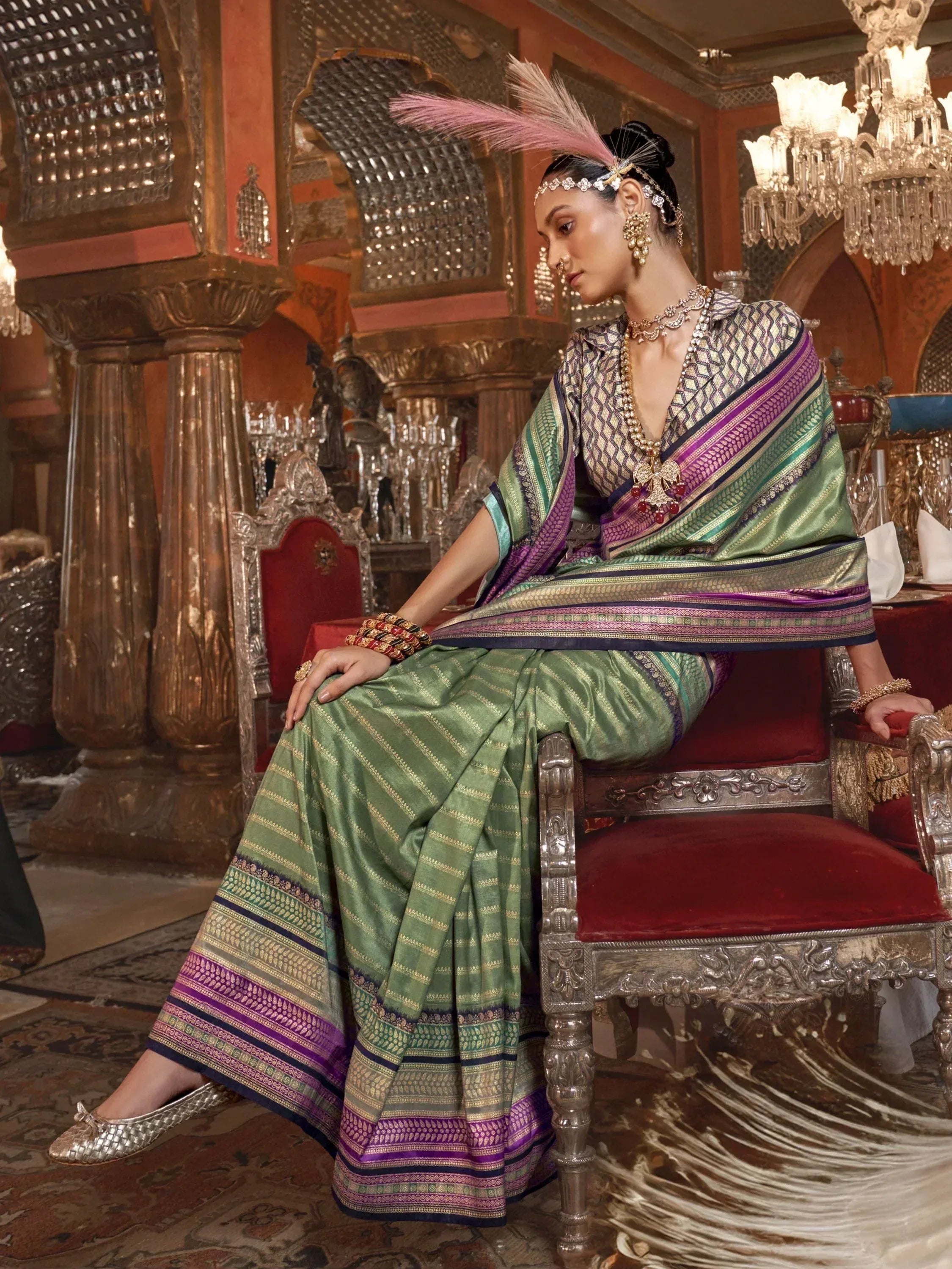 Elegant green and purple ethnic saree with intricate patterns, paired with traditional jewelry and feathered headpiece.