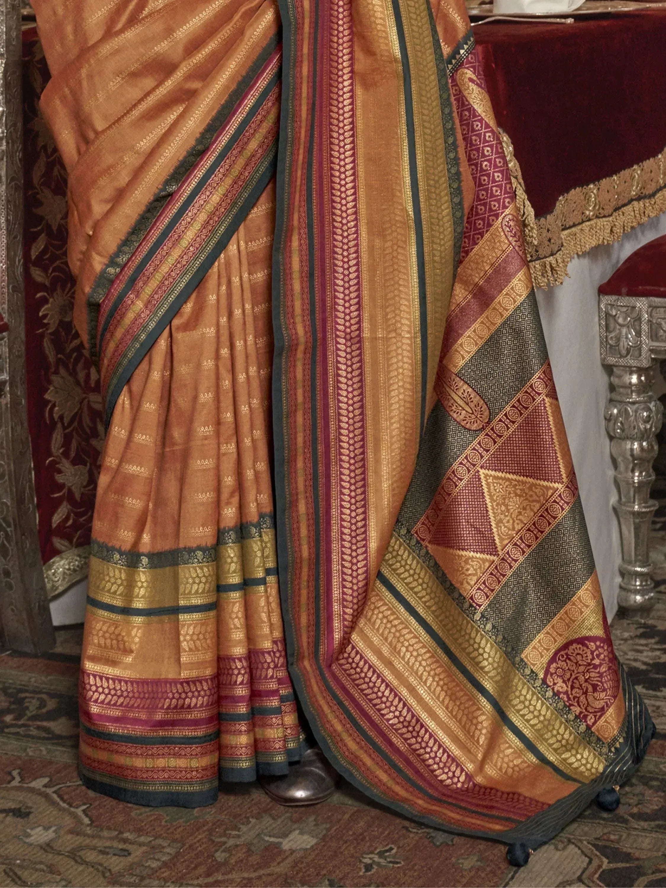 Richly woven Indian saree in gold, maroon, and teal with intricate temple border patterns, perfect for ethnic occasions.