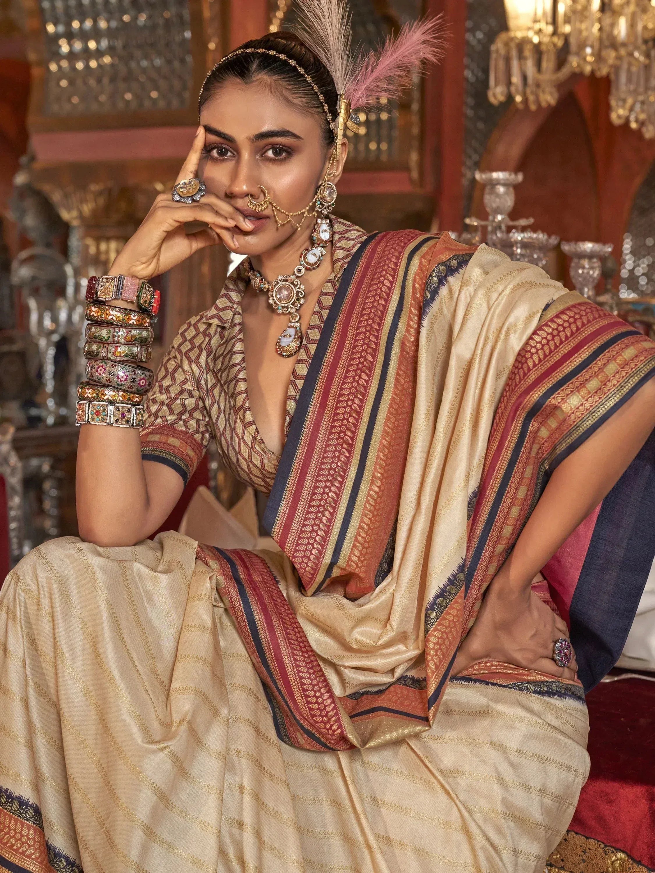 Elegant woman in traditional Indian saree with intricate embroidery, feather headpiece, and statement jewelry.