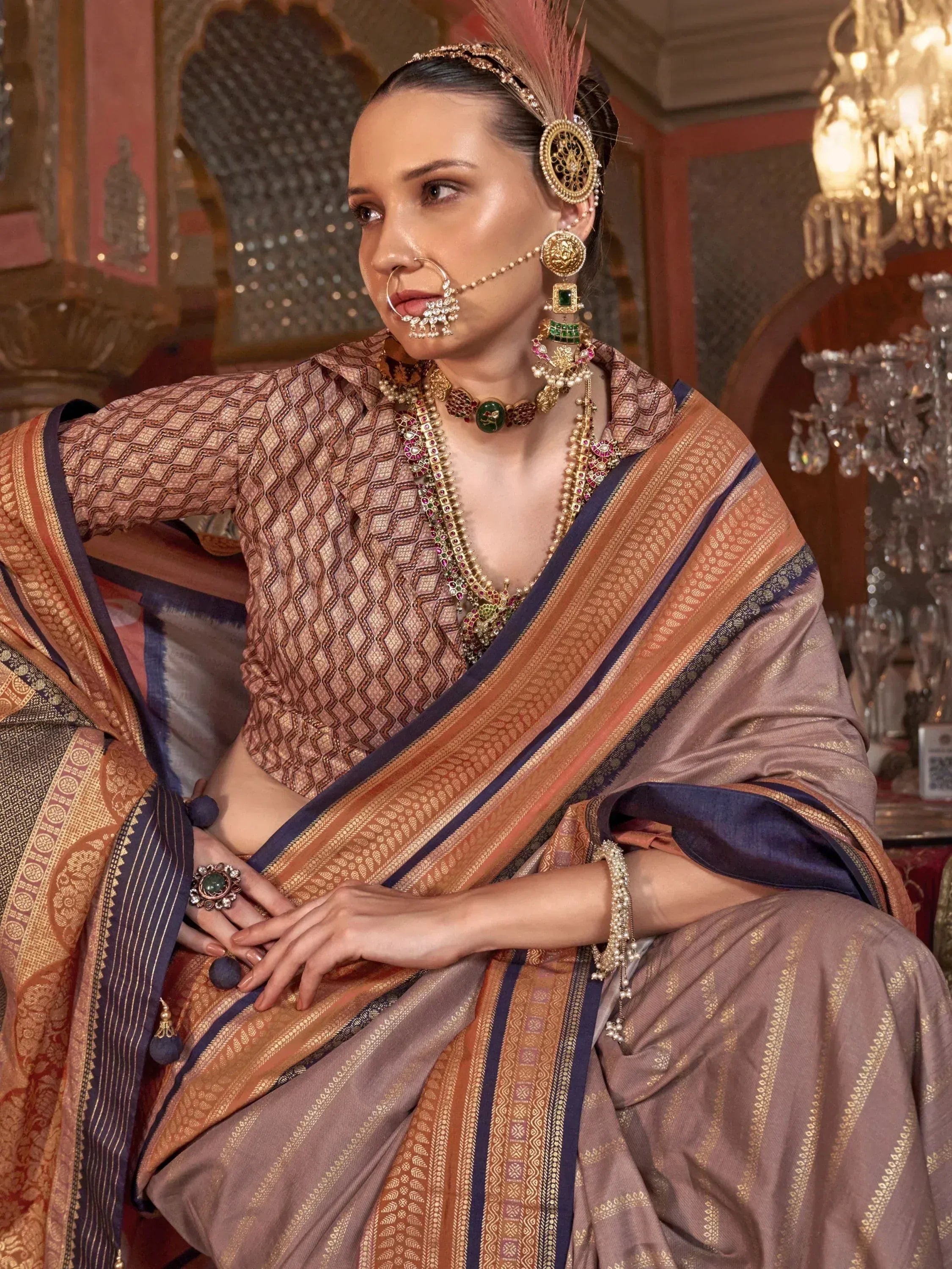 Elegant woman in traditional Indian saree with intricate gold jewelry and feathered headpiece, styled for festive occasions.