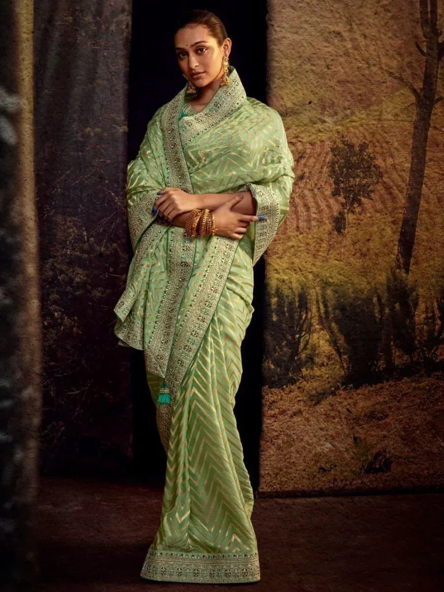Mint green designer saree with gold chevron pattern and embroidered border, styled with traditional jewelry