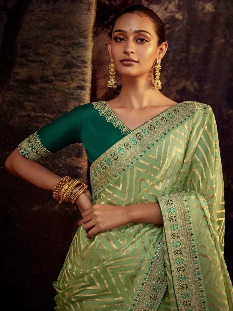 Green embroidered saree with gold zigzag pattern and matching blouse, styled with traditional jewelry