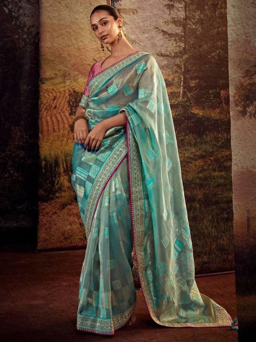 Woman in elegant turquoise ethnic saree with geometric print and embroidered border, perfect for Indian occasions.