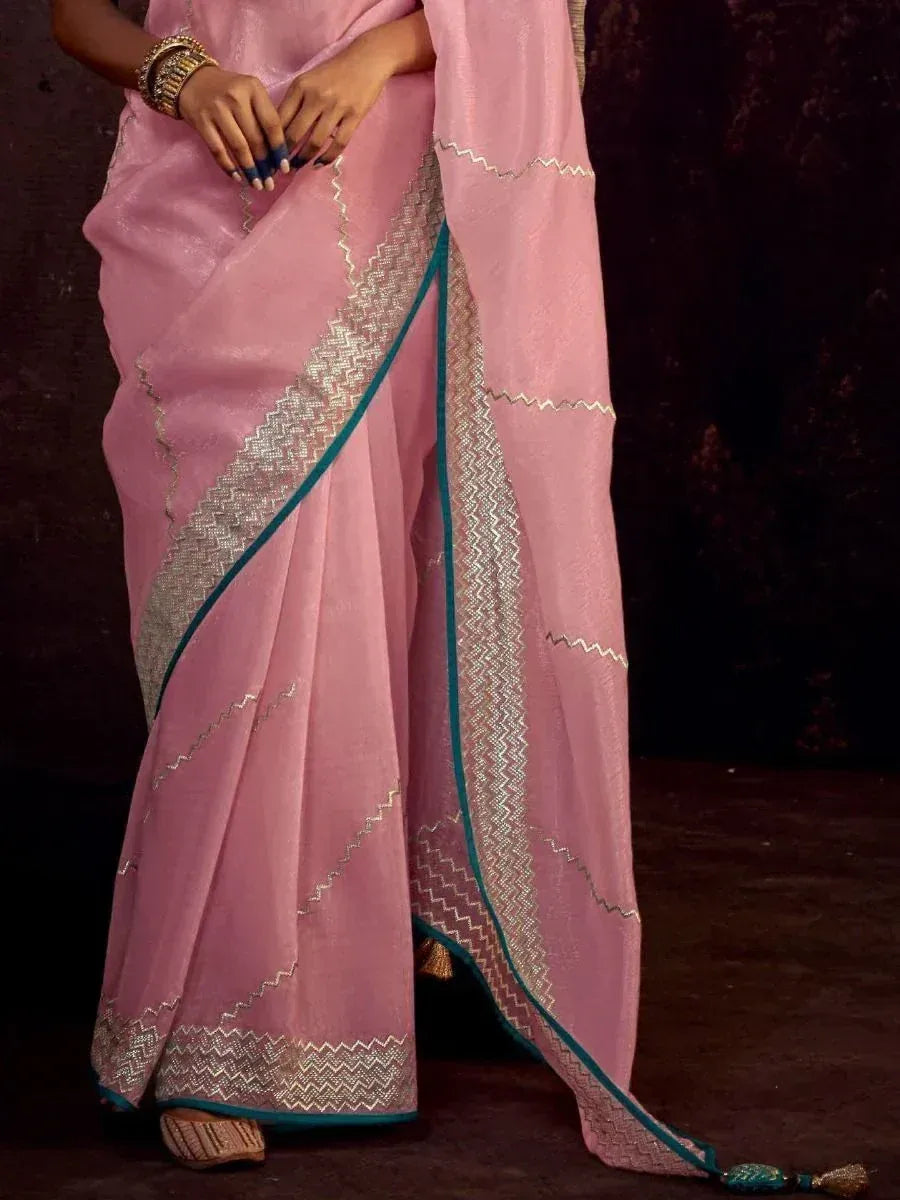 Pink saree with silver zigzag embroidery and teal border, styled with bangles and ethnic footwear