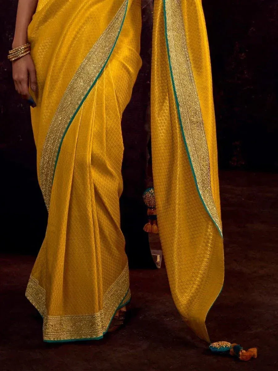 Yellow designer saree with gold zari border and teal trim, ethnic wear for women