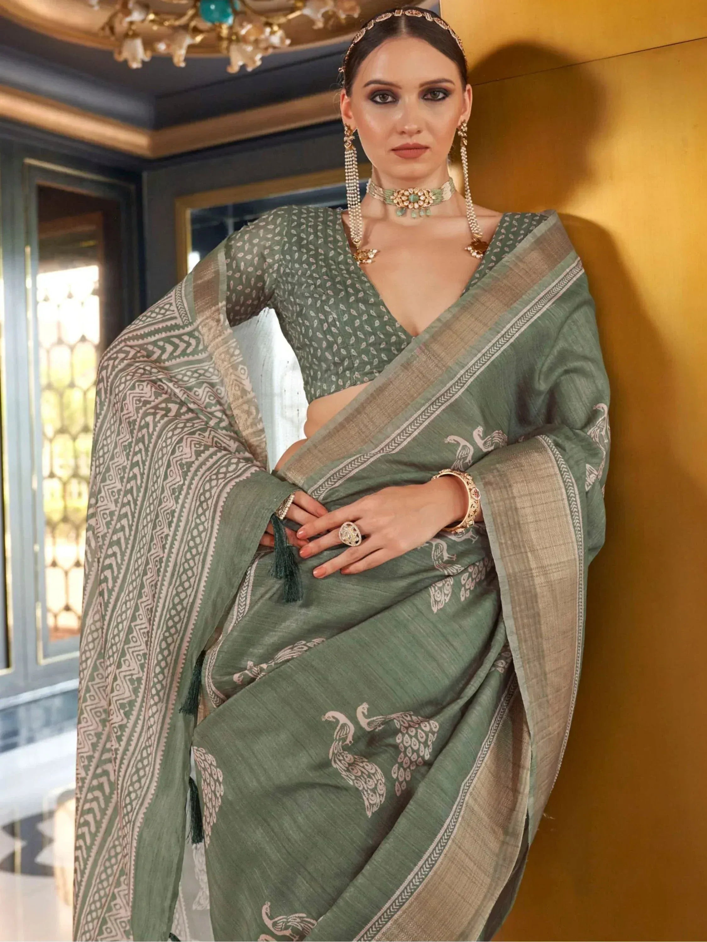 Elegant green saree with peacock print and geometric border, paired with matching blouse and traditional jewelry
