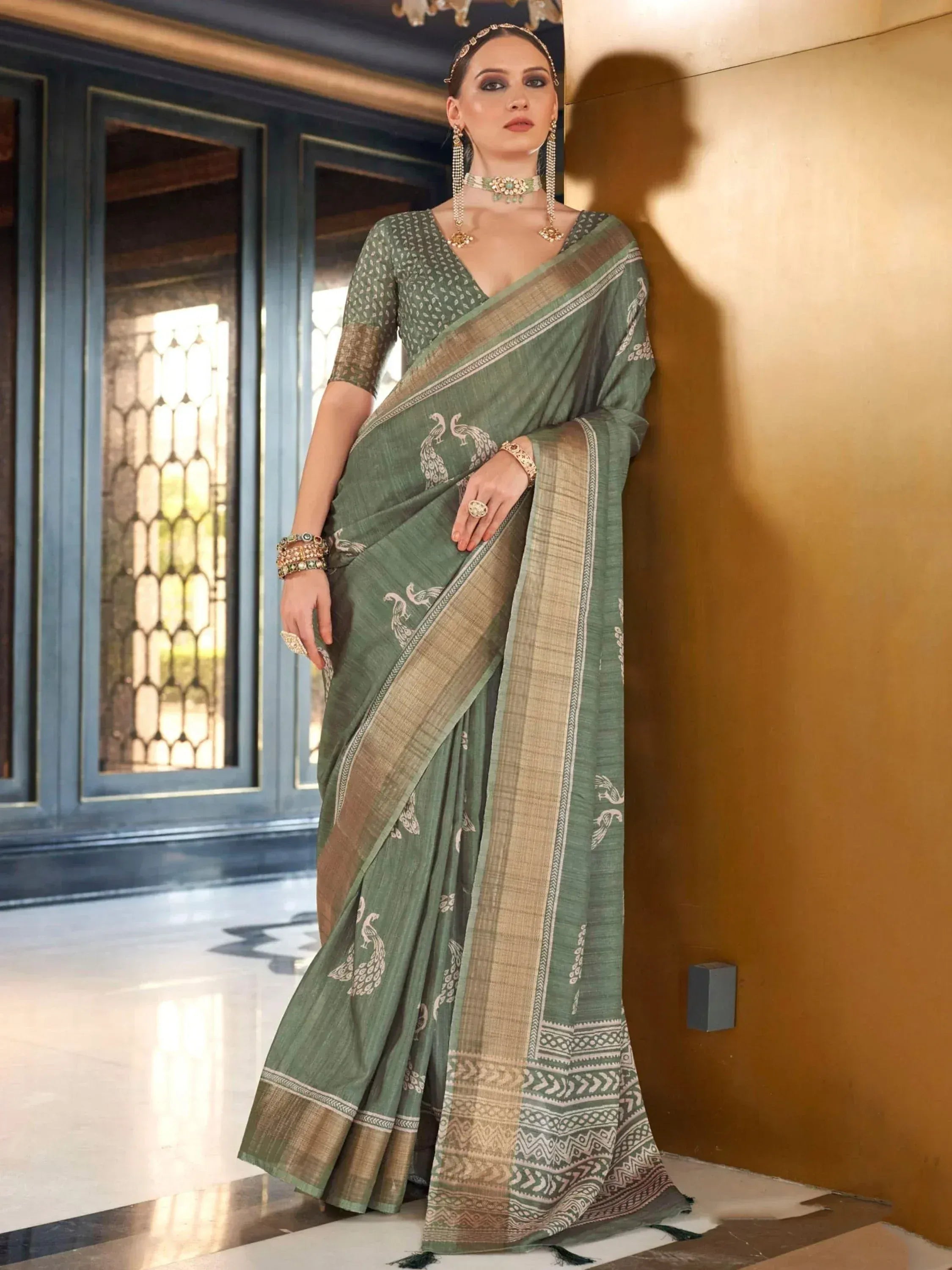 Green ethnic saree with peacock print and gold border, paired with designer jewelry for traditional Indian wear