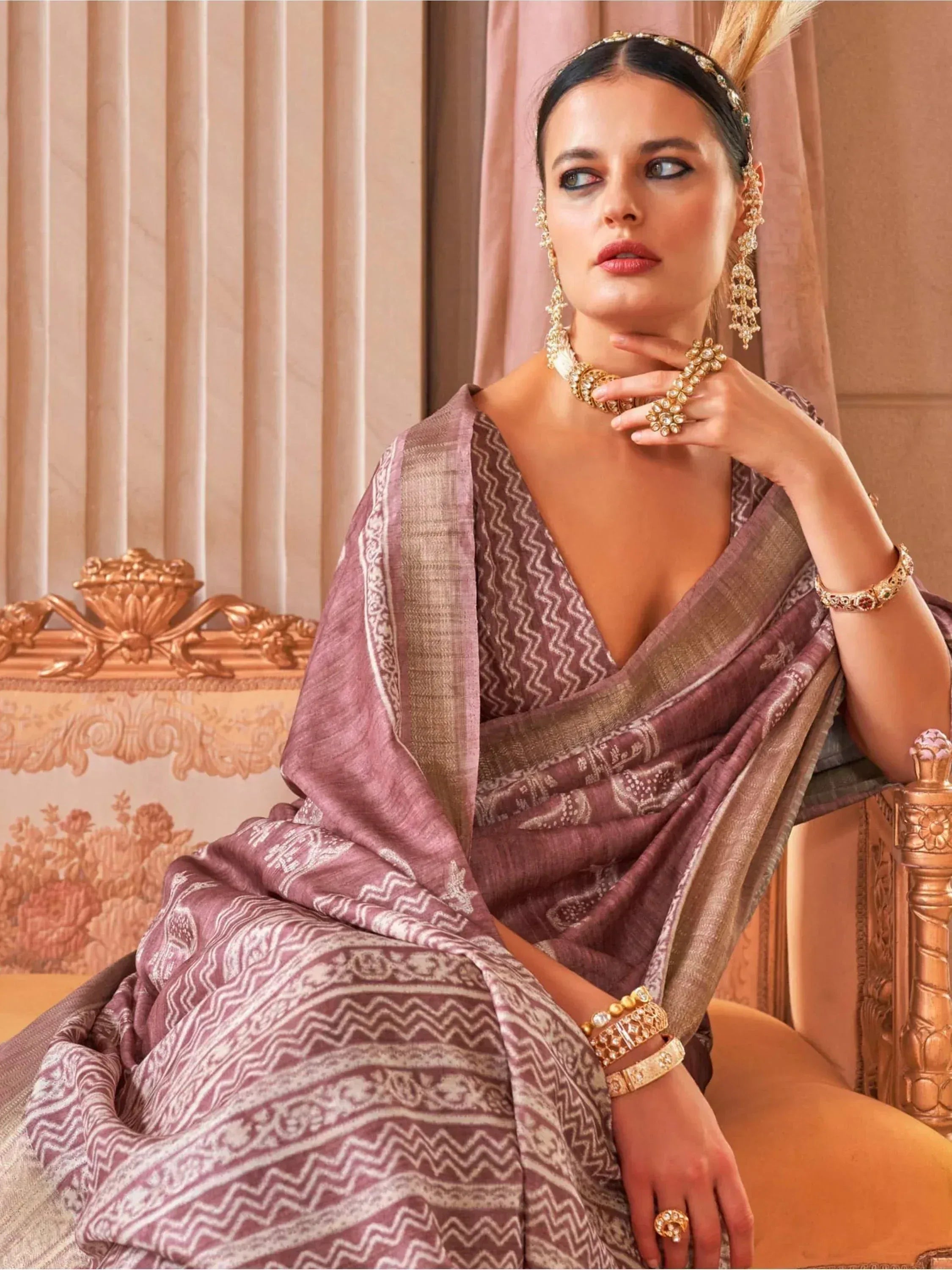 Elegant woman in mauve printed saree with gold jewelry, showcasing Indian ethnic wear style