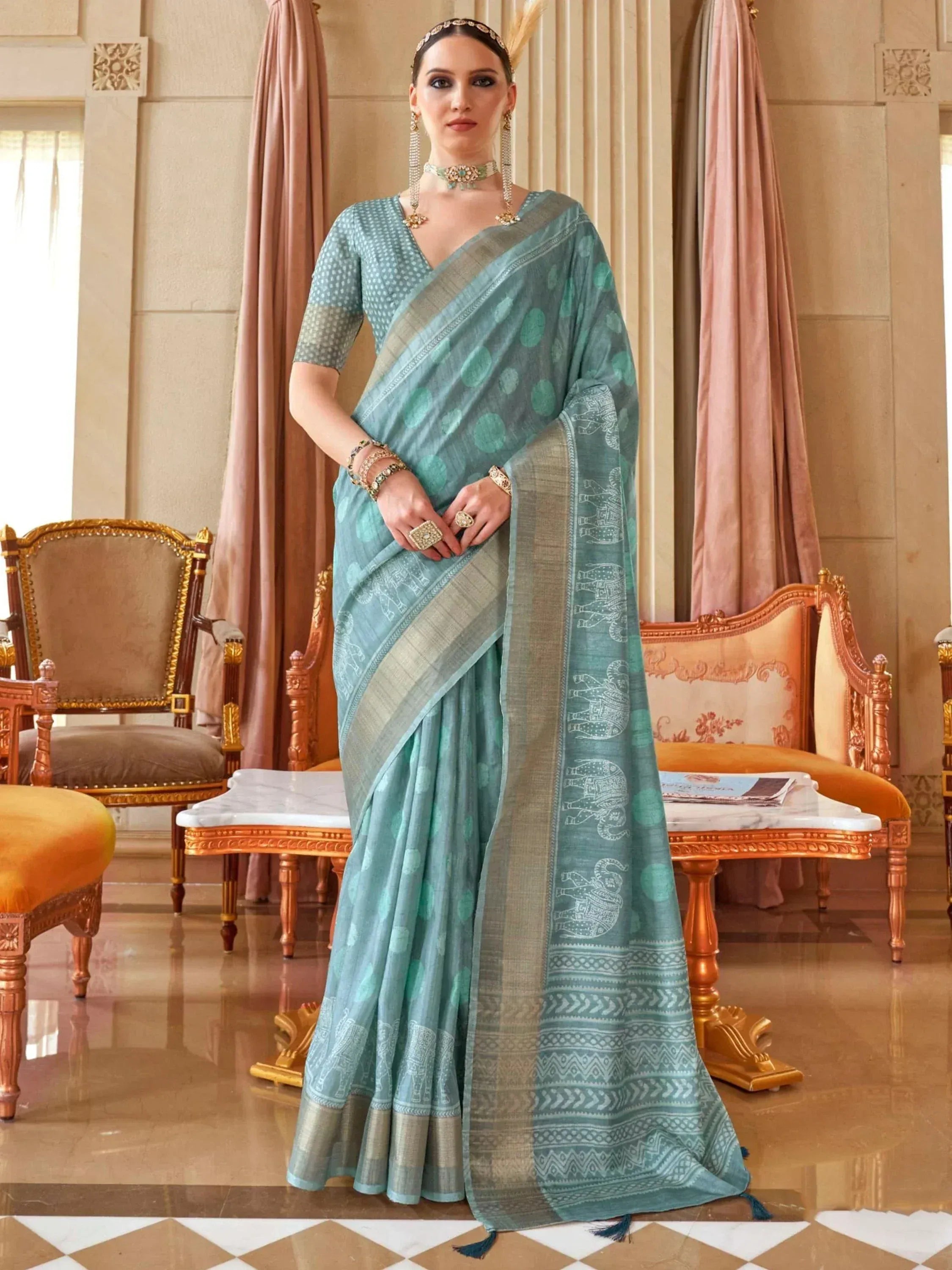 Elegant teal saree with elephant print and gold border, paired with matching blouse for Indian ethnic wear.