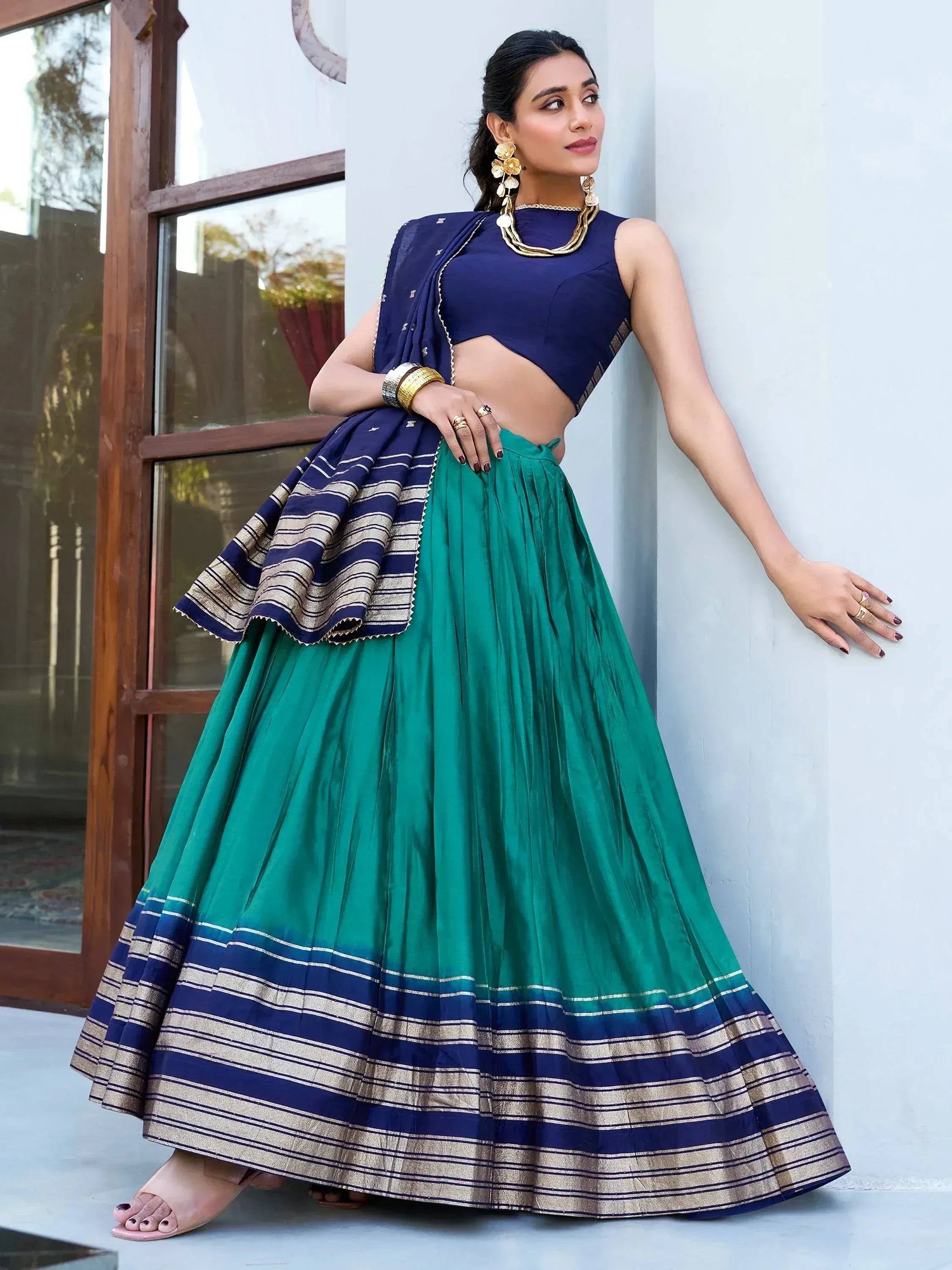 Woman in green and navy blue lehenga choli with gold stripes, styled for ethnic occasions