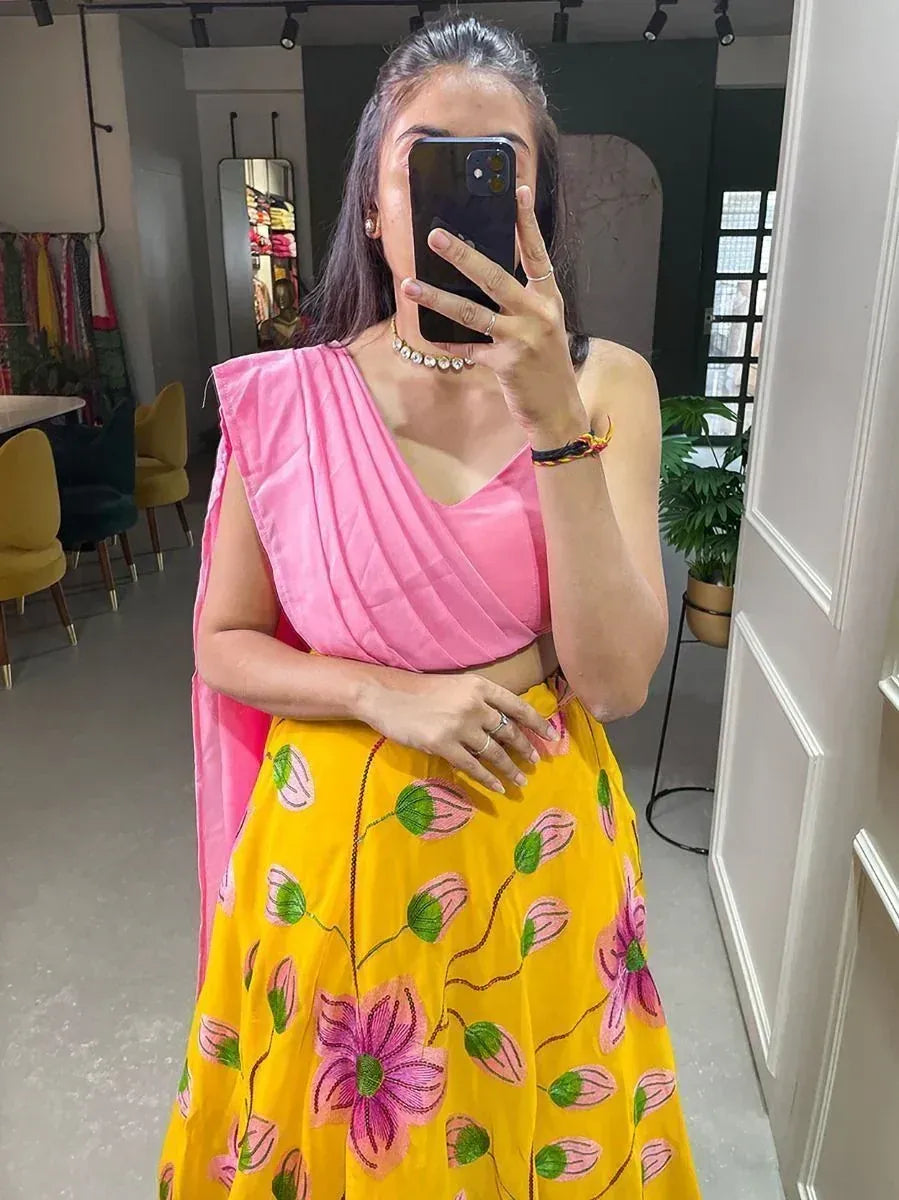 Woman in pink crop top and yellow floral lehenga, taking mirror selfie in boutique