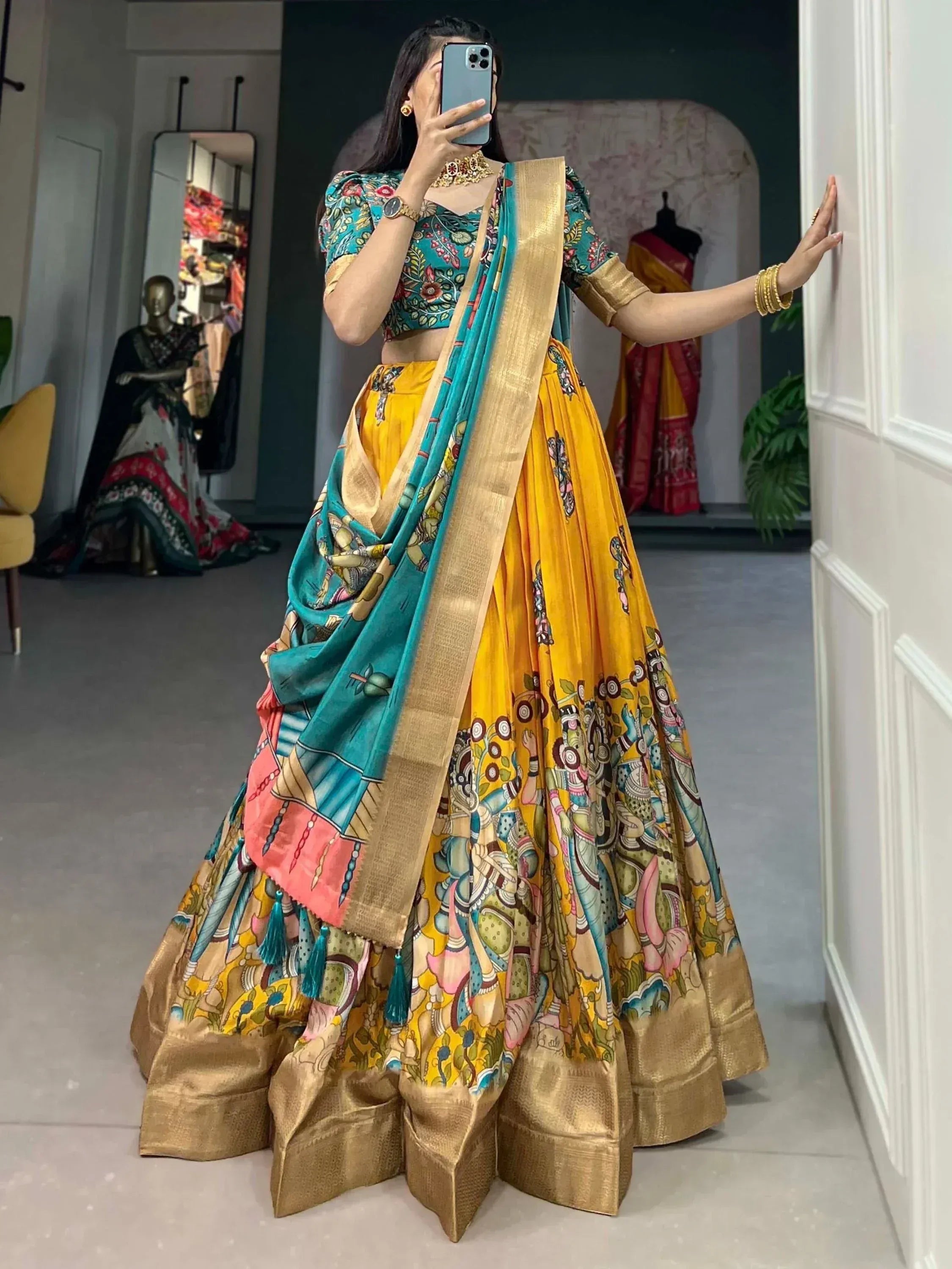 Woman in vibrant yellow and teal printed lehenga choli with gold border, perfect for Indian ethnic occasions.