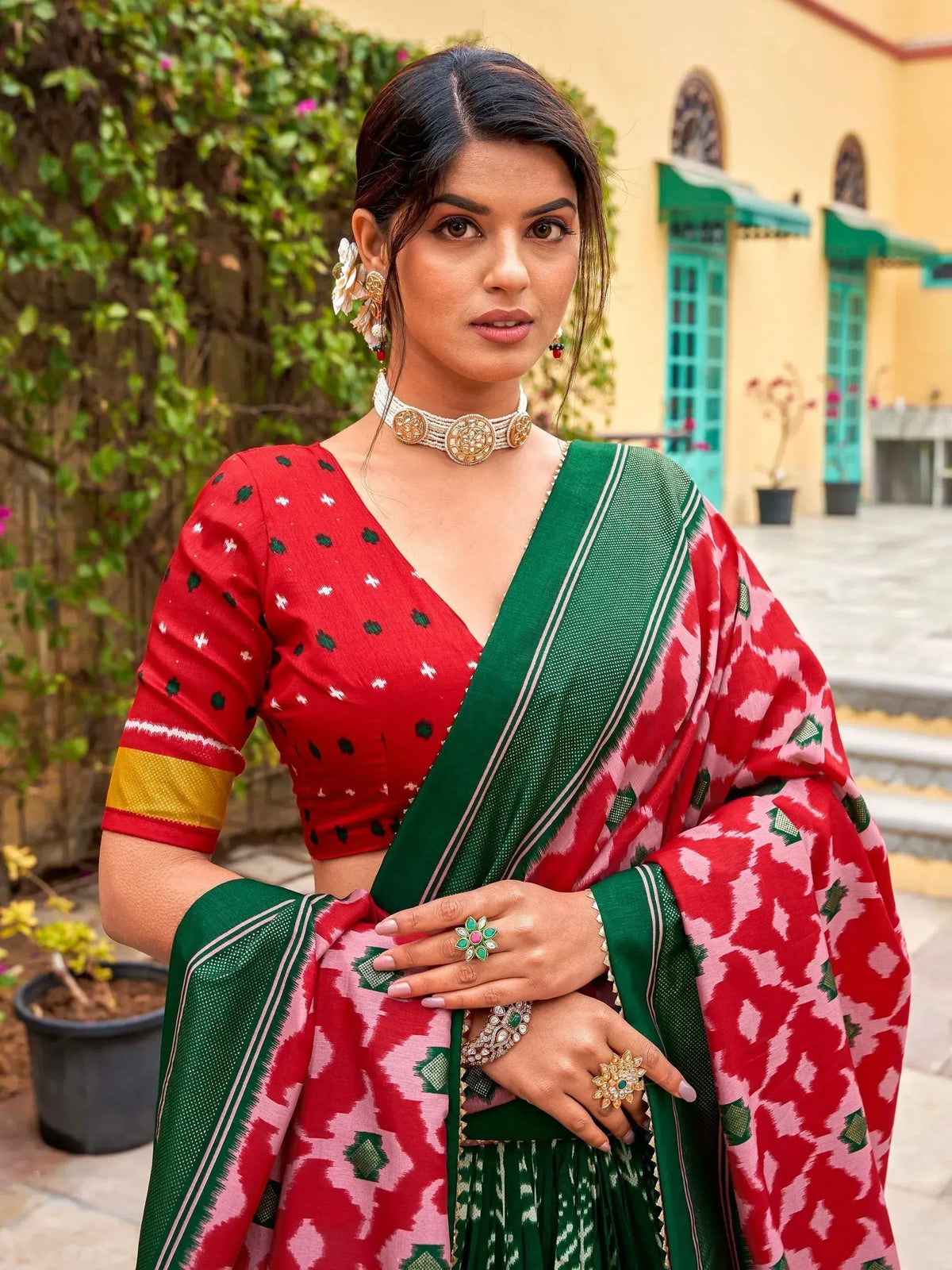 Woman in red and green printed saree with ethnic jewelry, traditional Indian wear