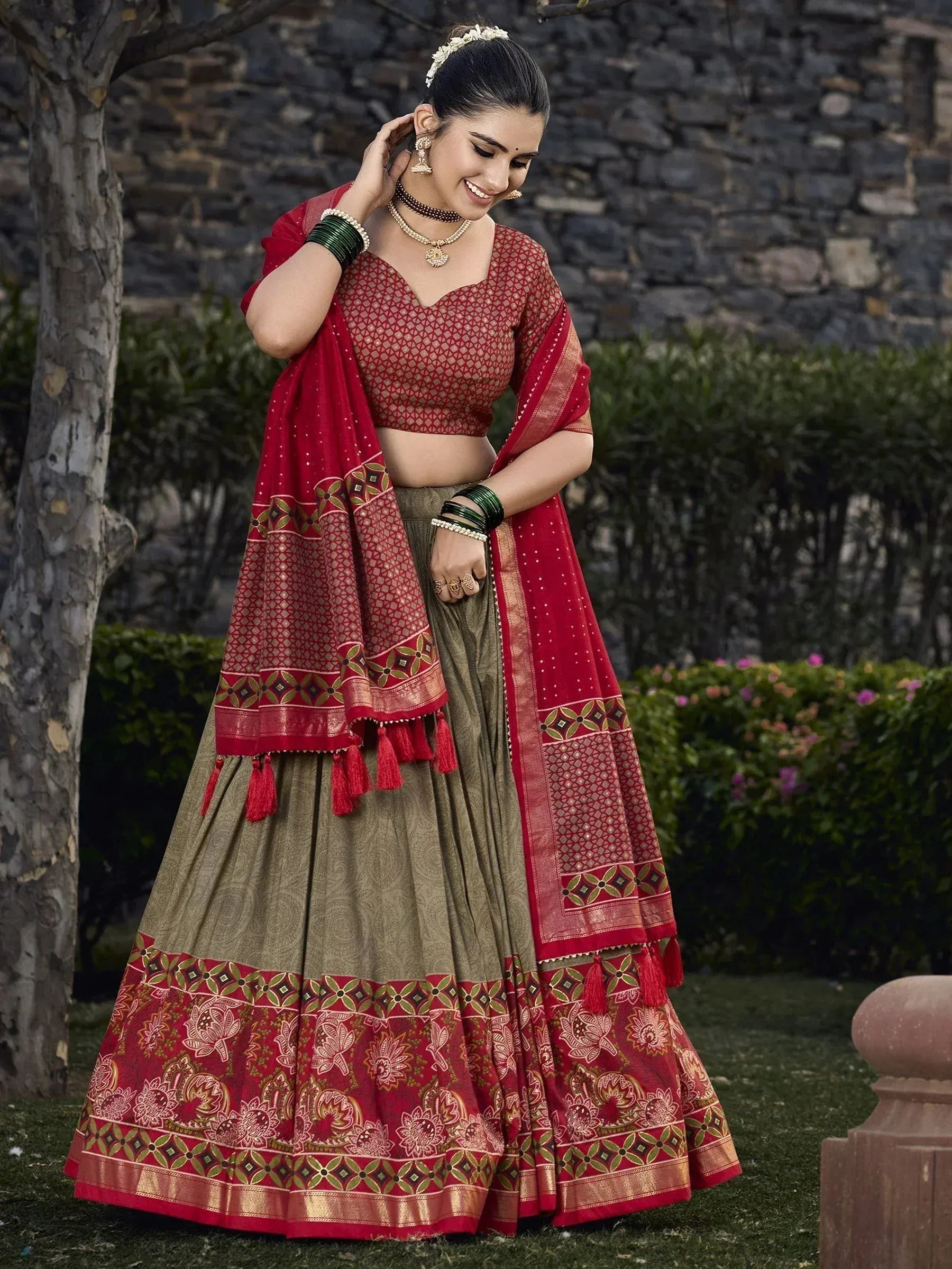 Red and olive green designer lehenga choli with intricate embroidery and tassels, perfect for Indian ethnic wear.
