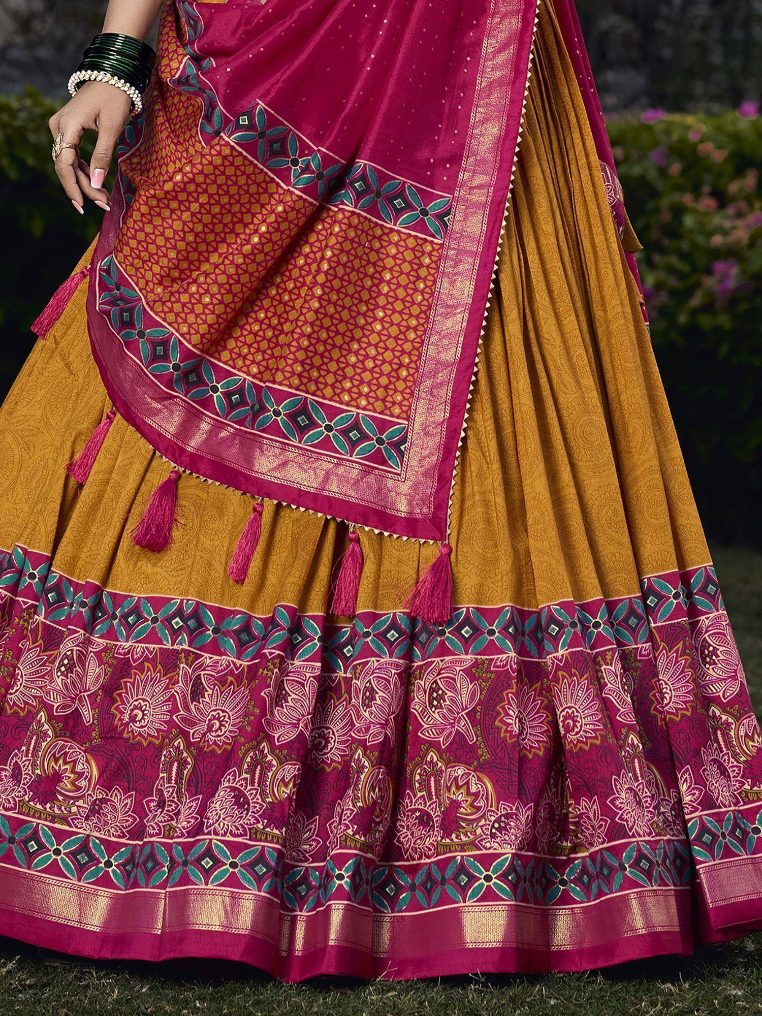 Magenta and mustard Indian lehenga choli with floral print, tassels, and ethnic border detailing