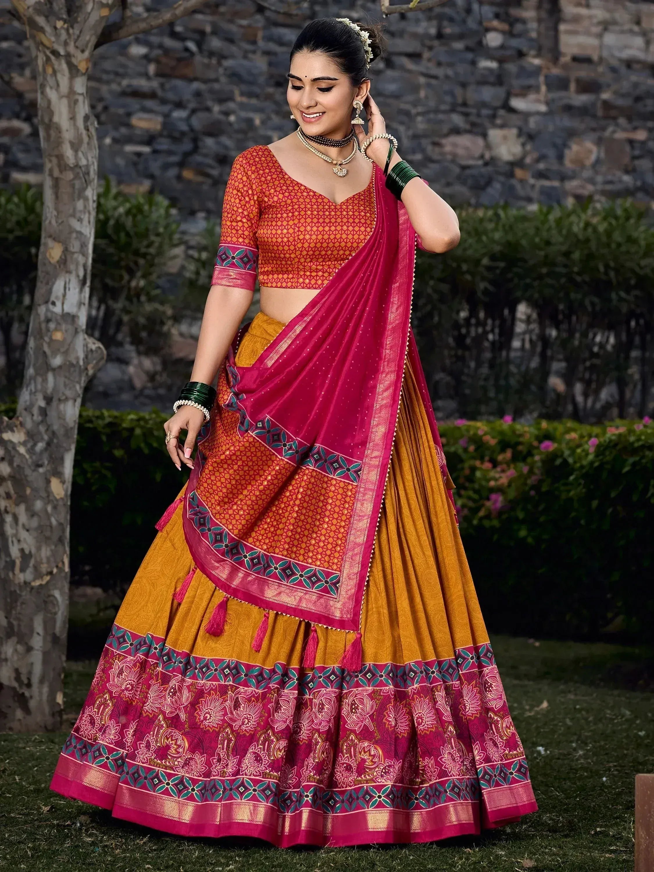Woman in vibrant Indian lehenga choli with pink and gold embroidery, perfect for ethnic occasions