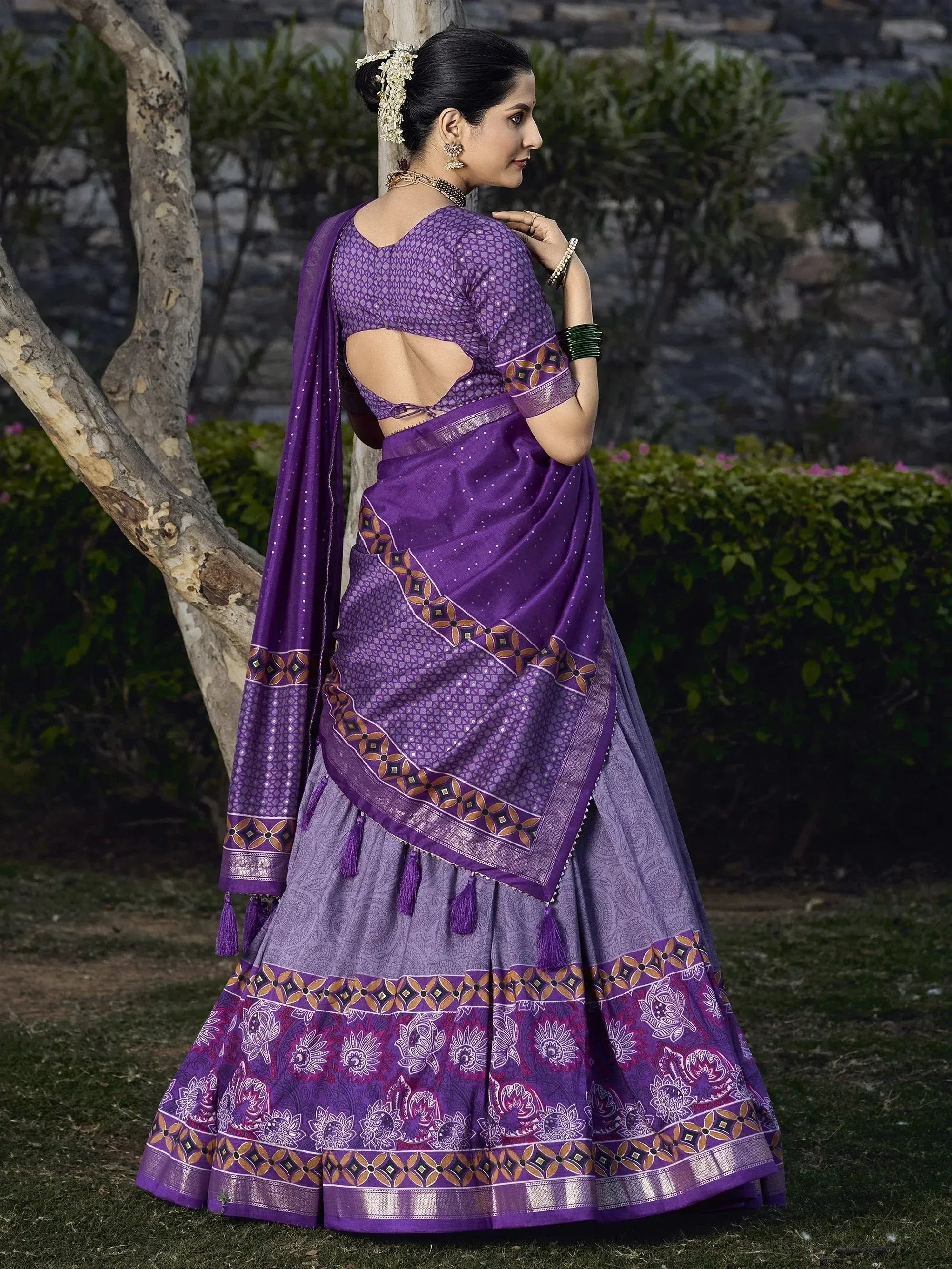 Purple designer lehenga choli with back cutout, floral print, and tassels, perfect for Indian ethnic wear occasions.