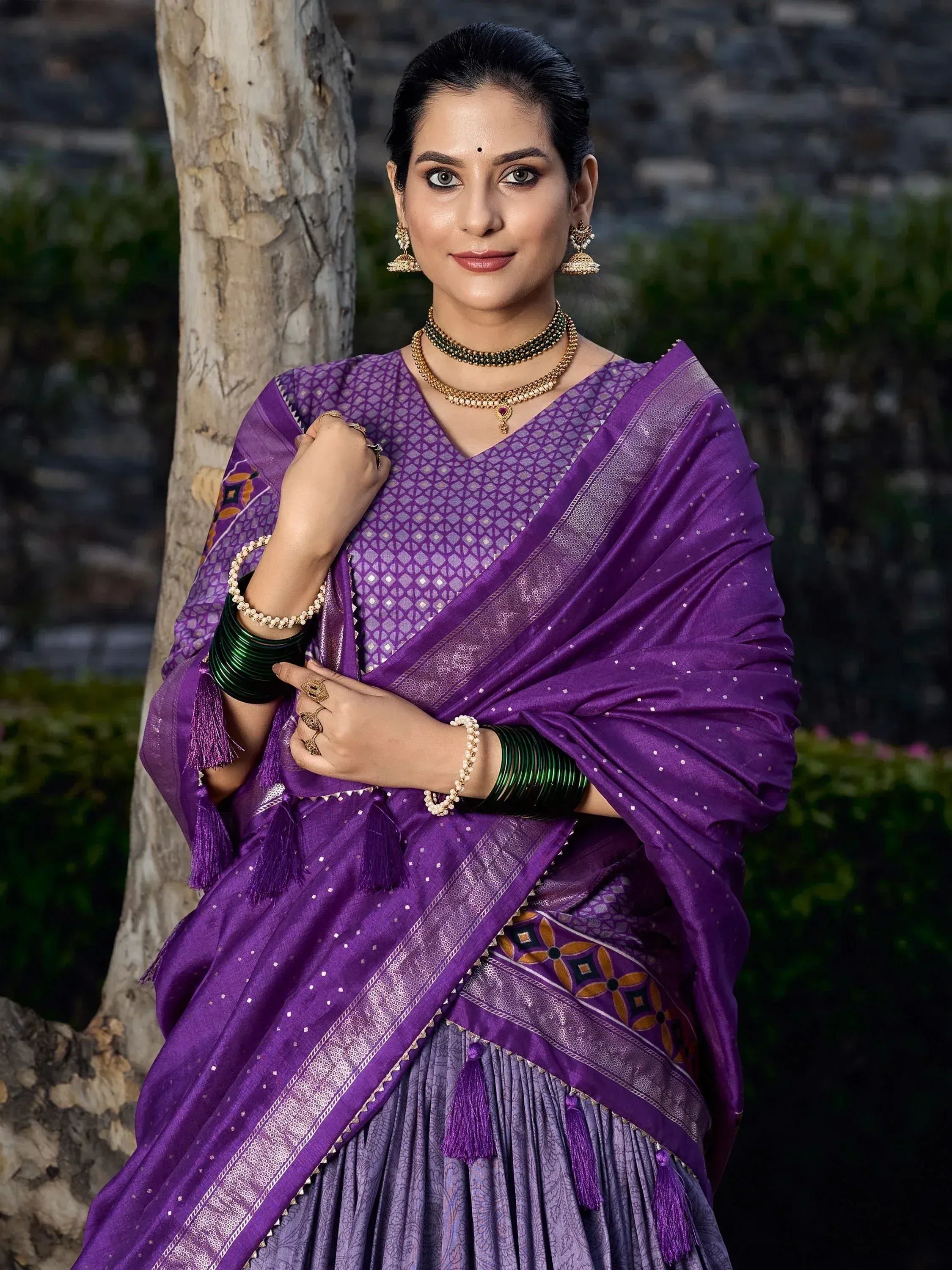 Woman in purple ethnic saree with gold embroidery and tassels, traditional Indian wear