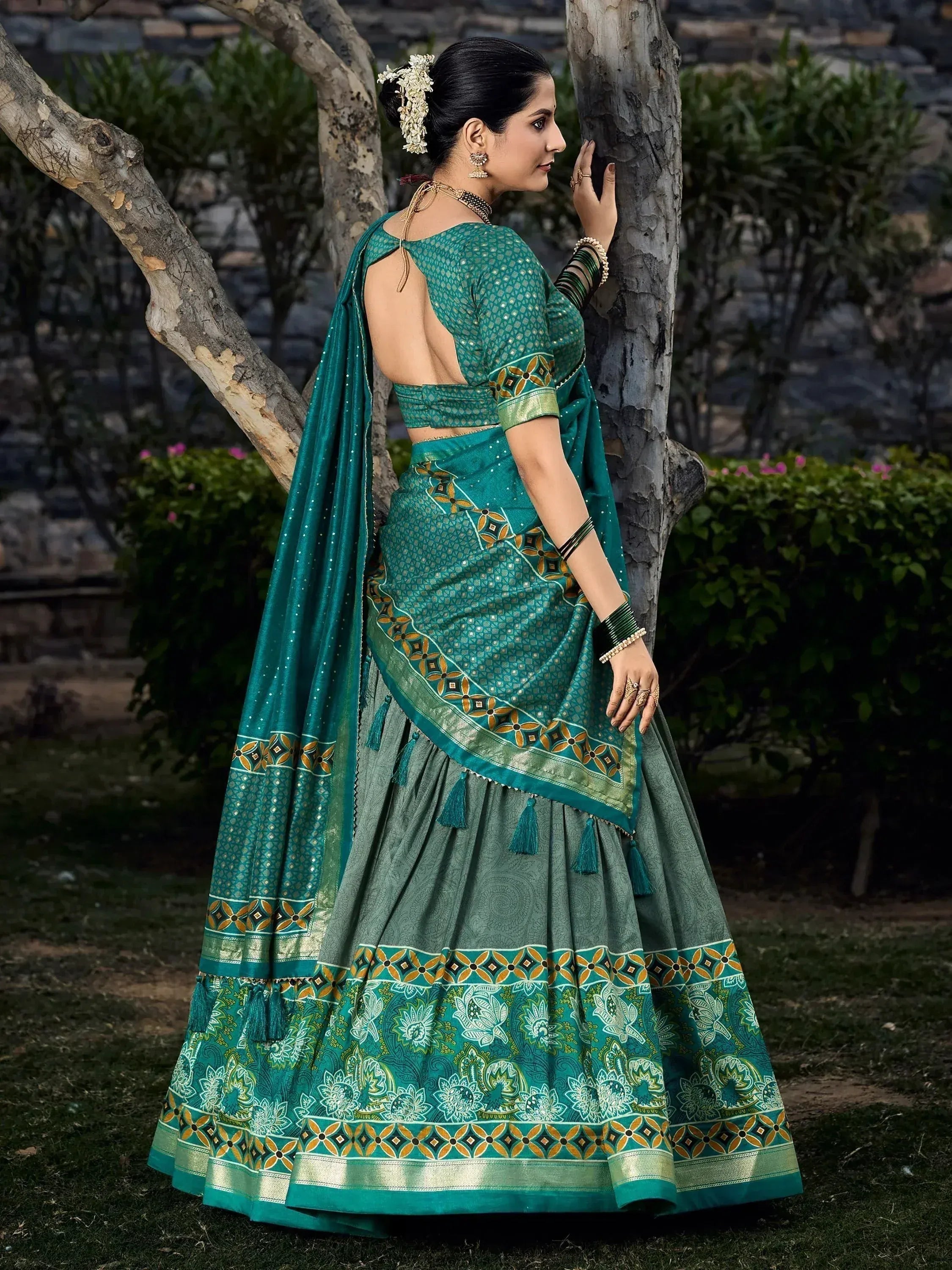 Teal green designer lehenga choli with floral print, tassels, and backless blouse, perfect for Indian ethnic wear