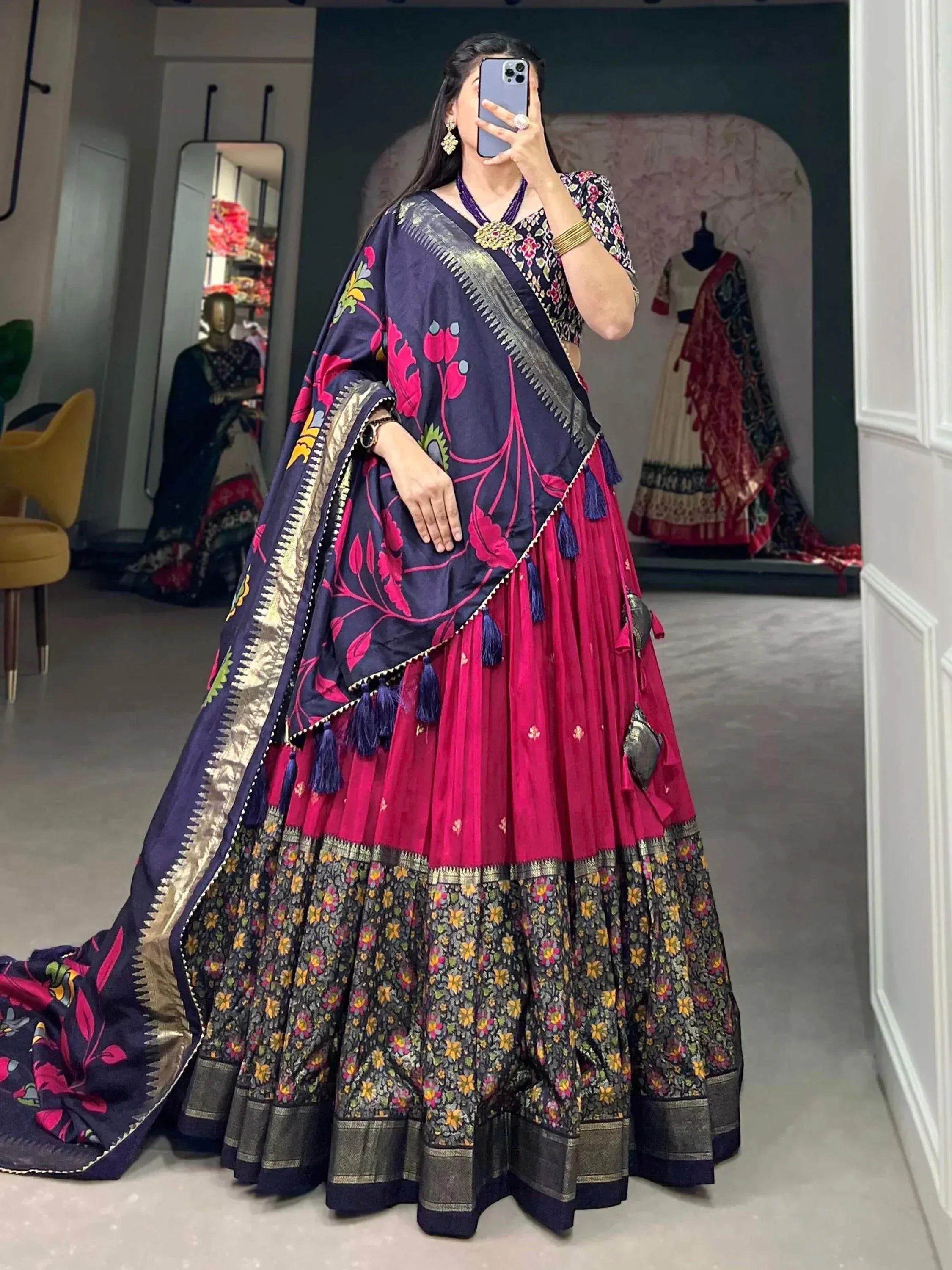 Woman in vibrant pink and navy floral lehenga choli with embroidered dupatta, perfect for Indian ethnic occasions.