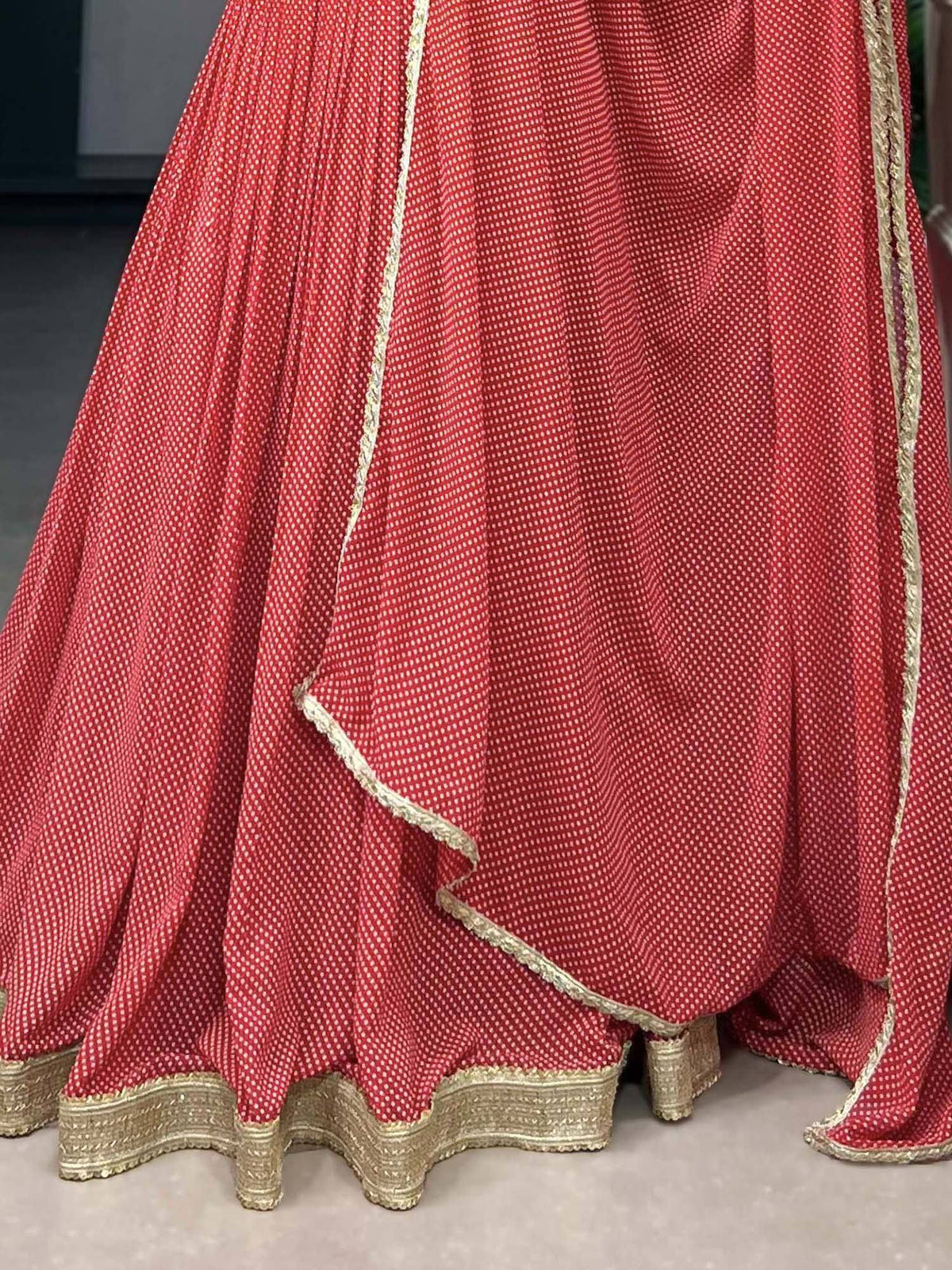Red ethnic lehenga with gold trim and dotted pattern, perfect for Indian weddings and festive occasions