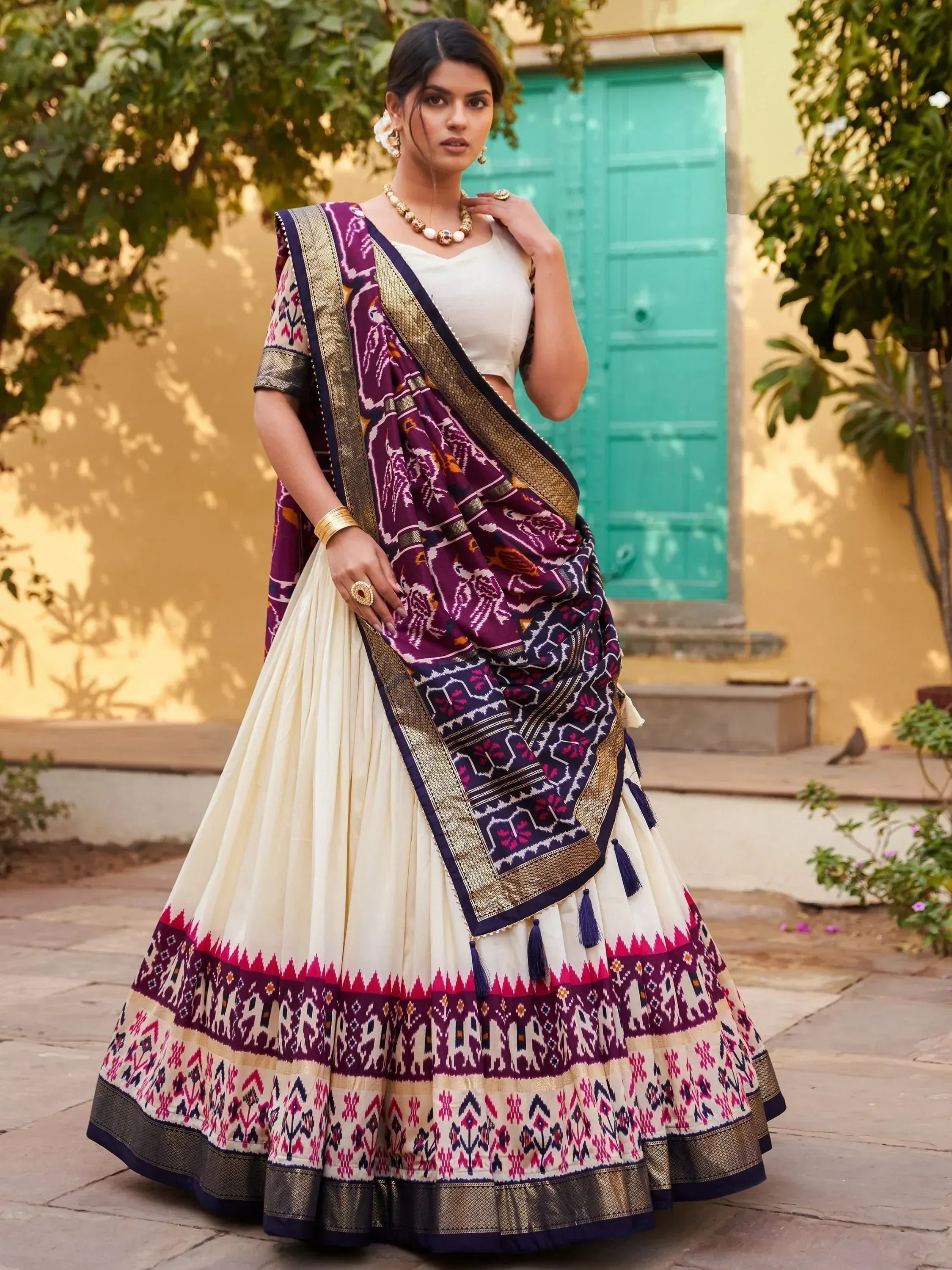 Woman in purple and cream ikat lehenga choli with gold border, traditional Indian ethnic wear