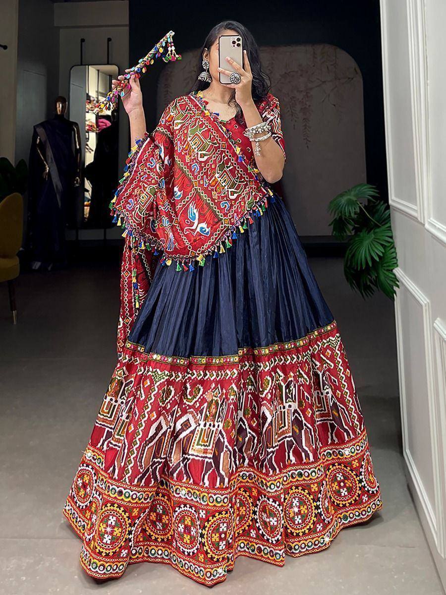 Vibrant red and navy blue embroidered lehenga choli with mirror work and tassels, perfect for festive occasions.