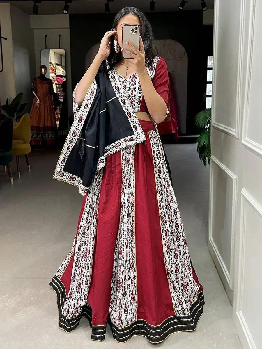 Woman in maroon and white printed lehenga choli with black dupatta, taking mirror selfie in boutique