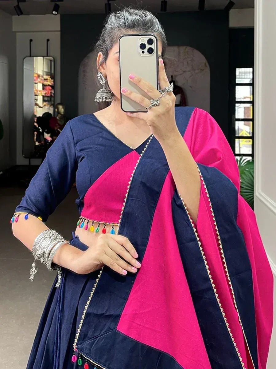 Woman in navy and pink ethnic lehenga choli with colorful tassels and silver jewelry, taking mirror selfie