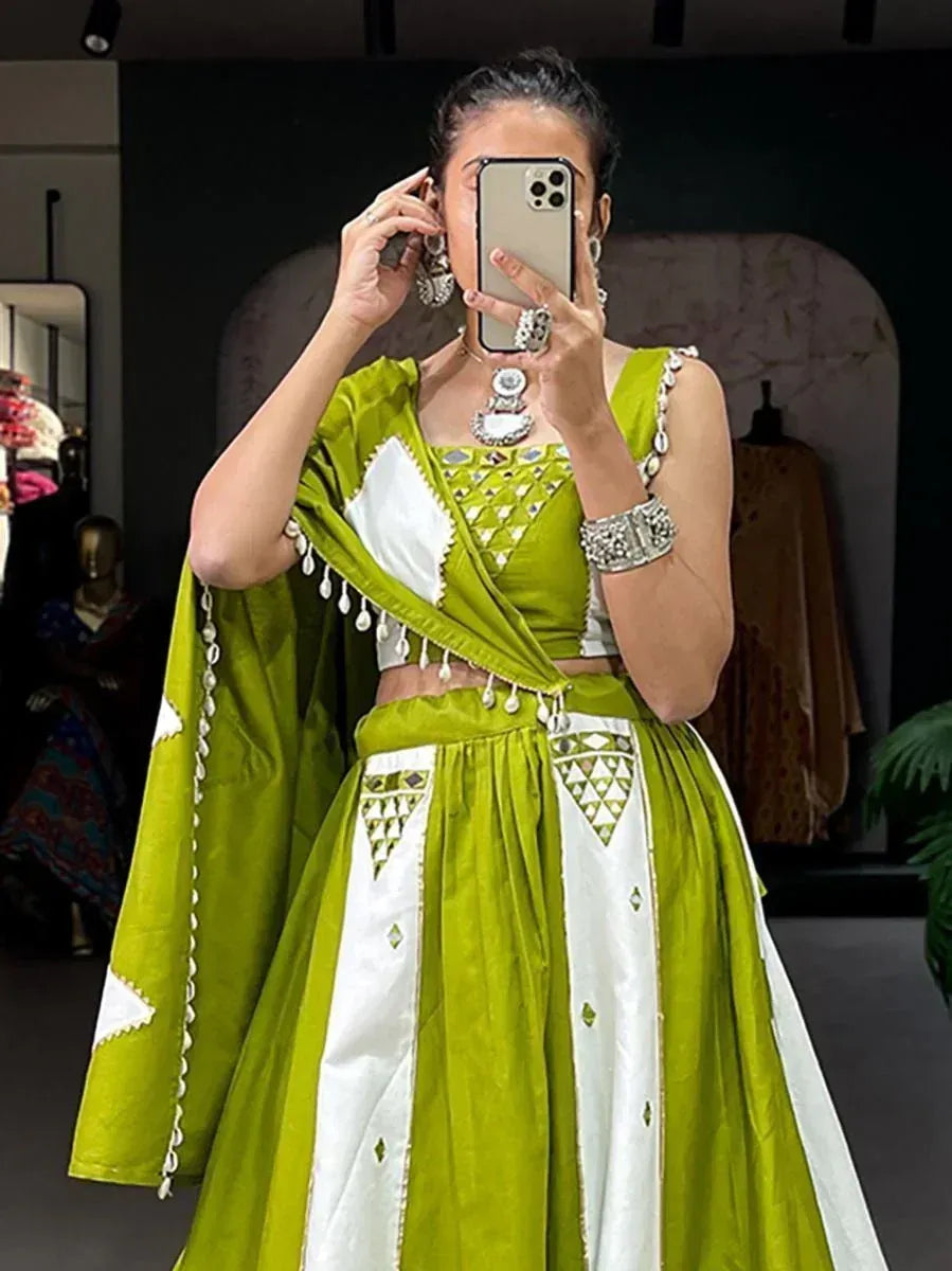 Green and white ethnic lehenga choli with mirror work and tassels, styled with traditional jewelry