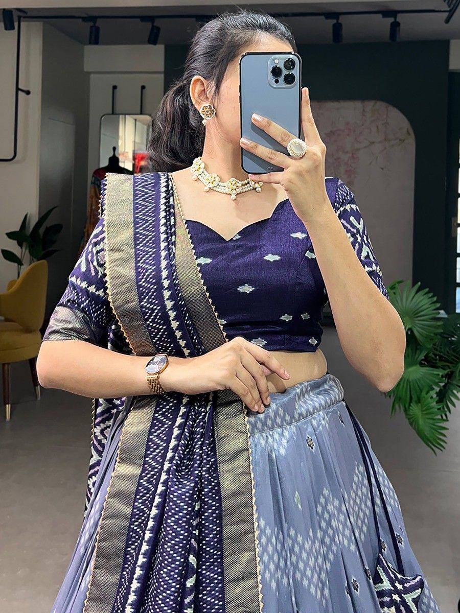 Woman in purple printed lehenga choli with gold trim, taking mirror selfie in boutique