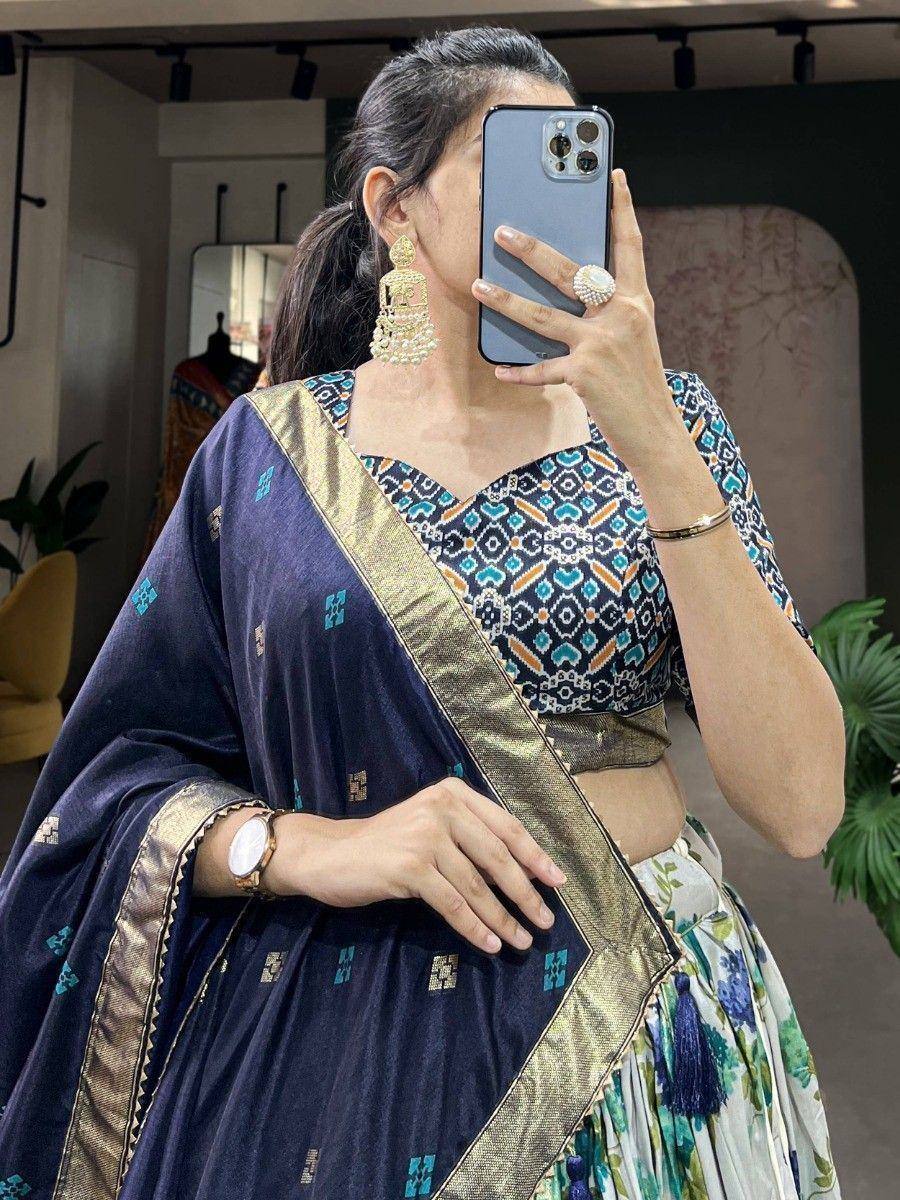 Woman in navy blue printed lehenga choli with gold border, floral skirt, and jhumka earrings