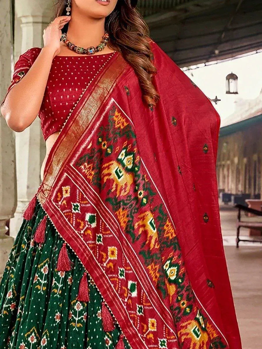 Red and green ethnic lehenga choli with intricate embroidery and tassels, perfect for festive occasions.
