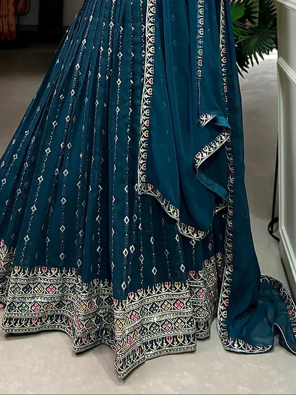 Teal designer lehenga choli with intricate embroidery and pleated skirt, perfect for Indian ethnic wear