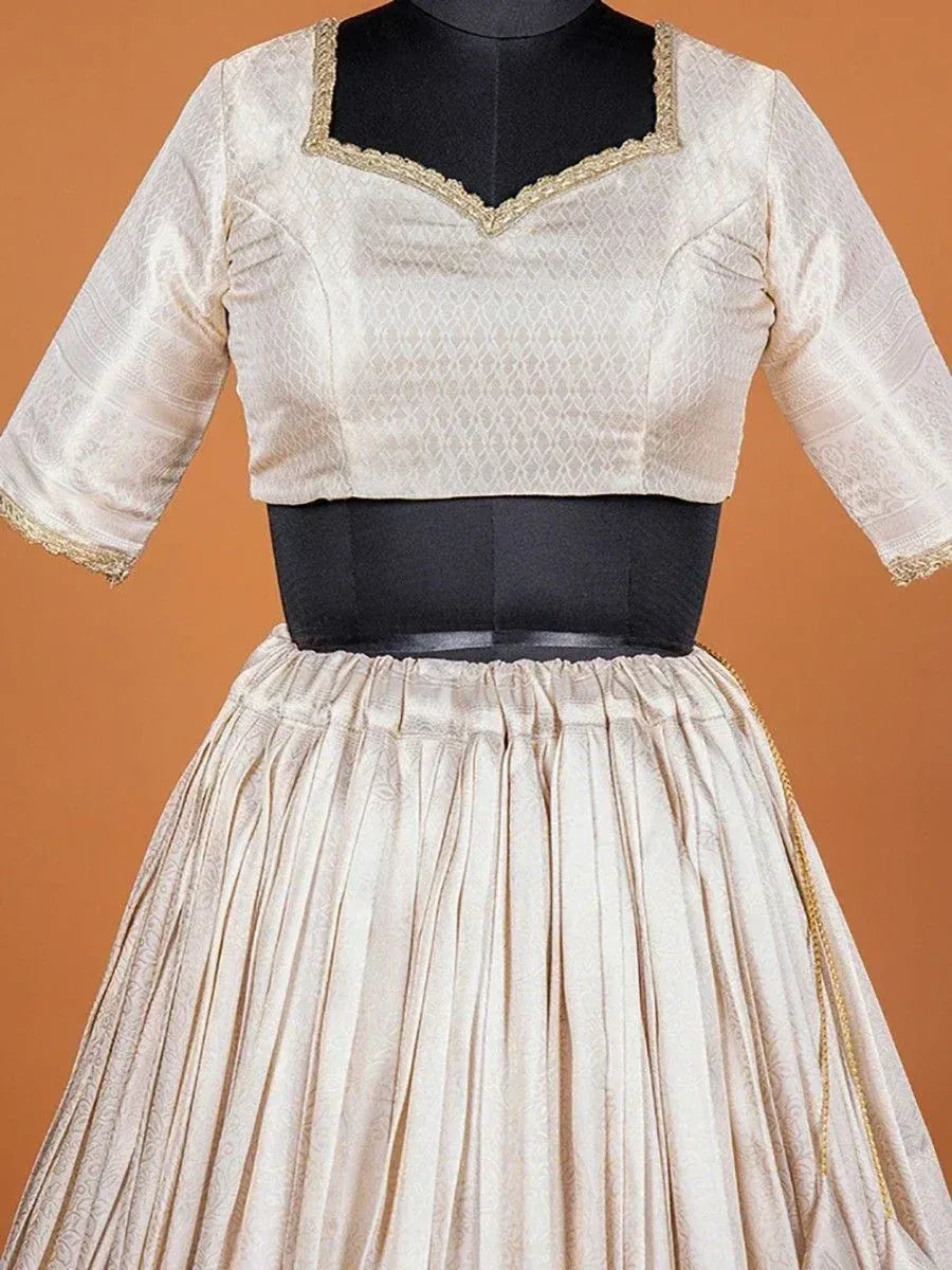 Cream ethnic lehenga choli with gold trim, pleated skirt, and V-neck blouse for Indian wear