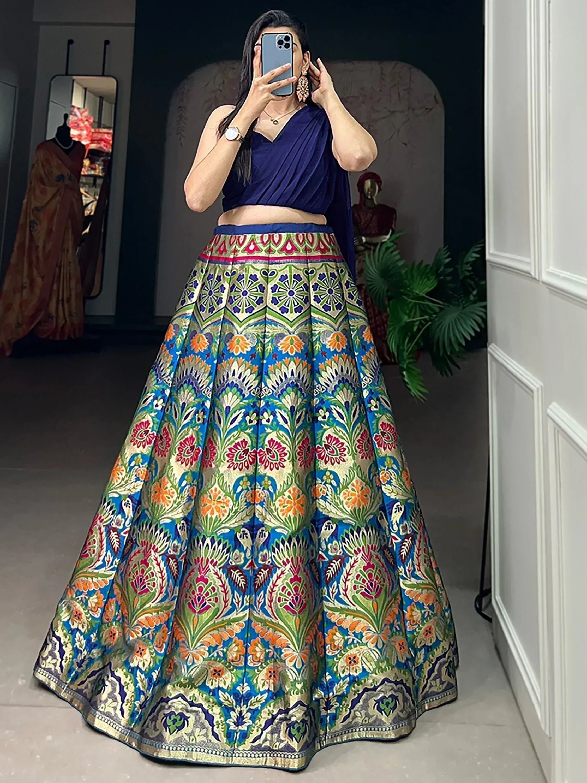 Woman in vibrant floral lehenga choli with blue crop top, ethnic Indian wear for festive occasions