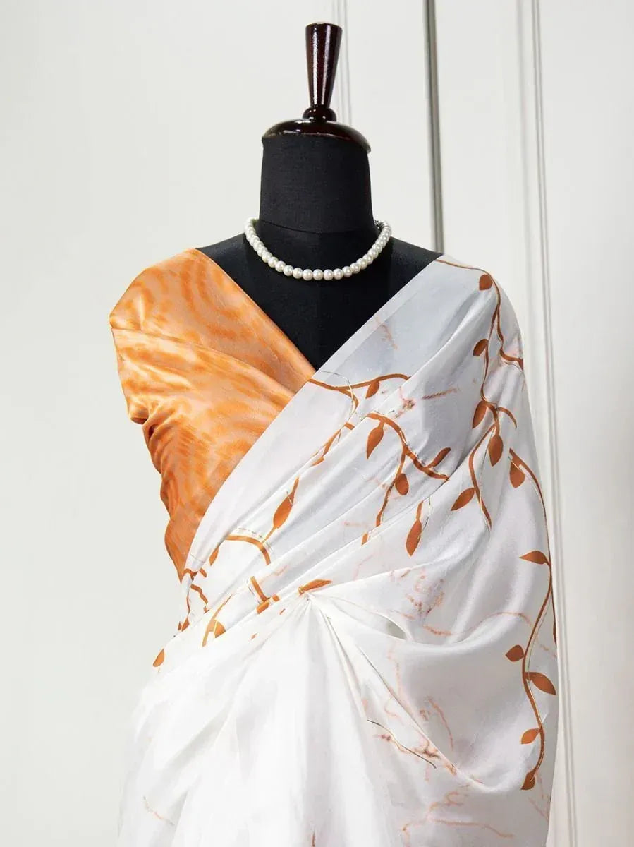 White saree with orange leaf print and matching blouse, styled on mannequin with pearl necklace
