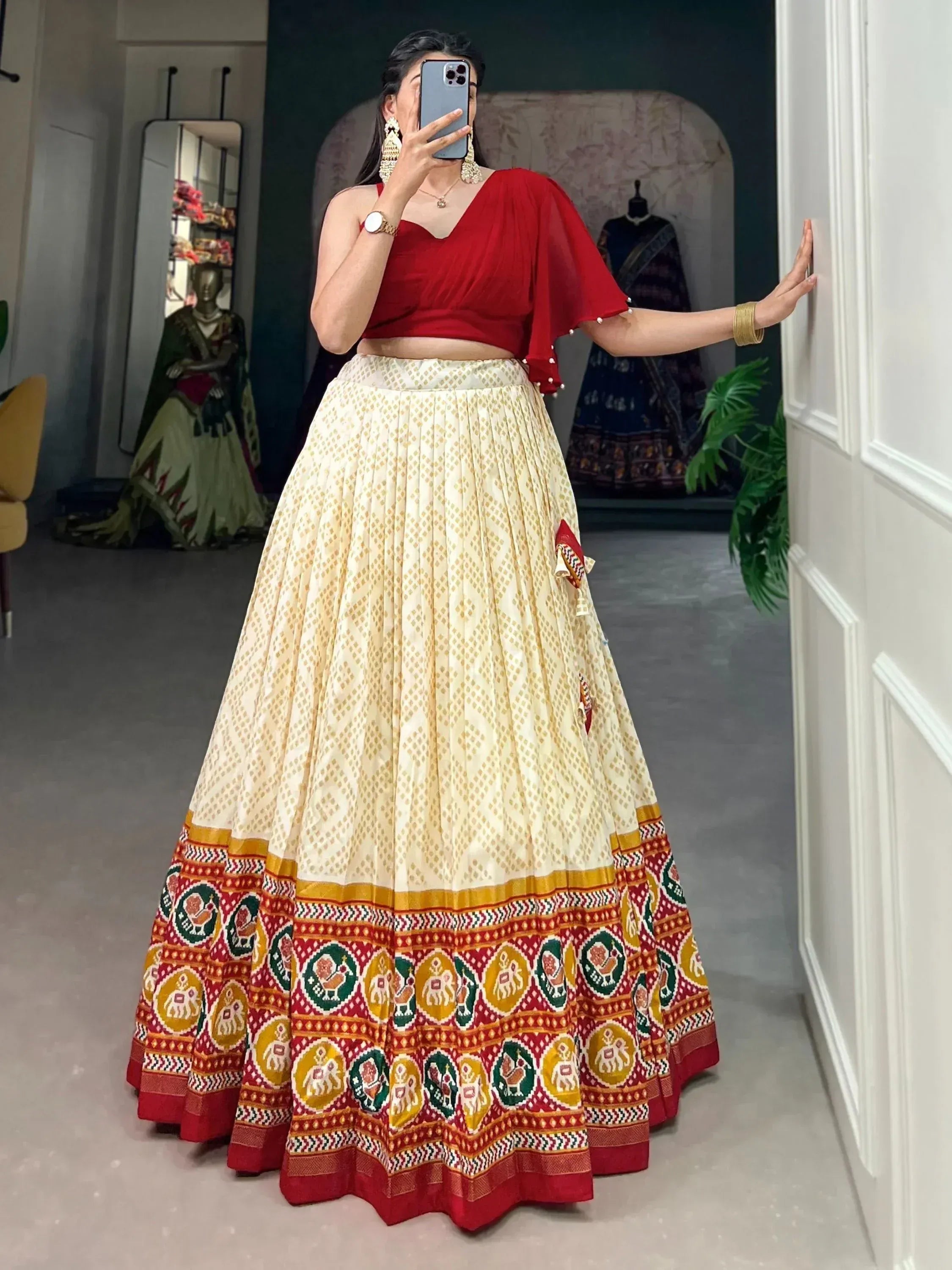 Woman in red crop top and cream pleated lehenga with colorful elephant print border, ethnic Indian wear