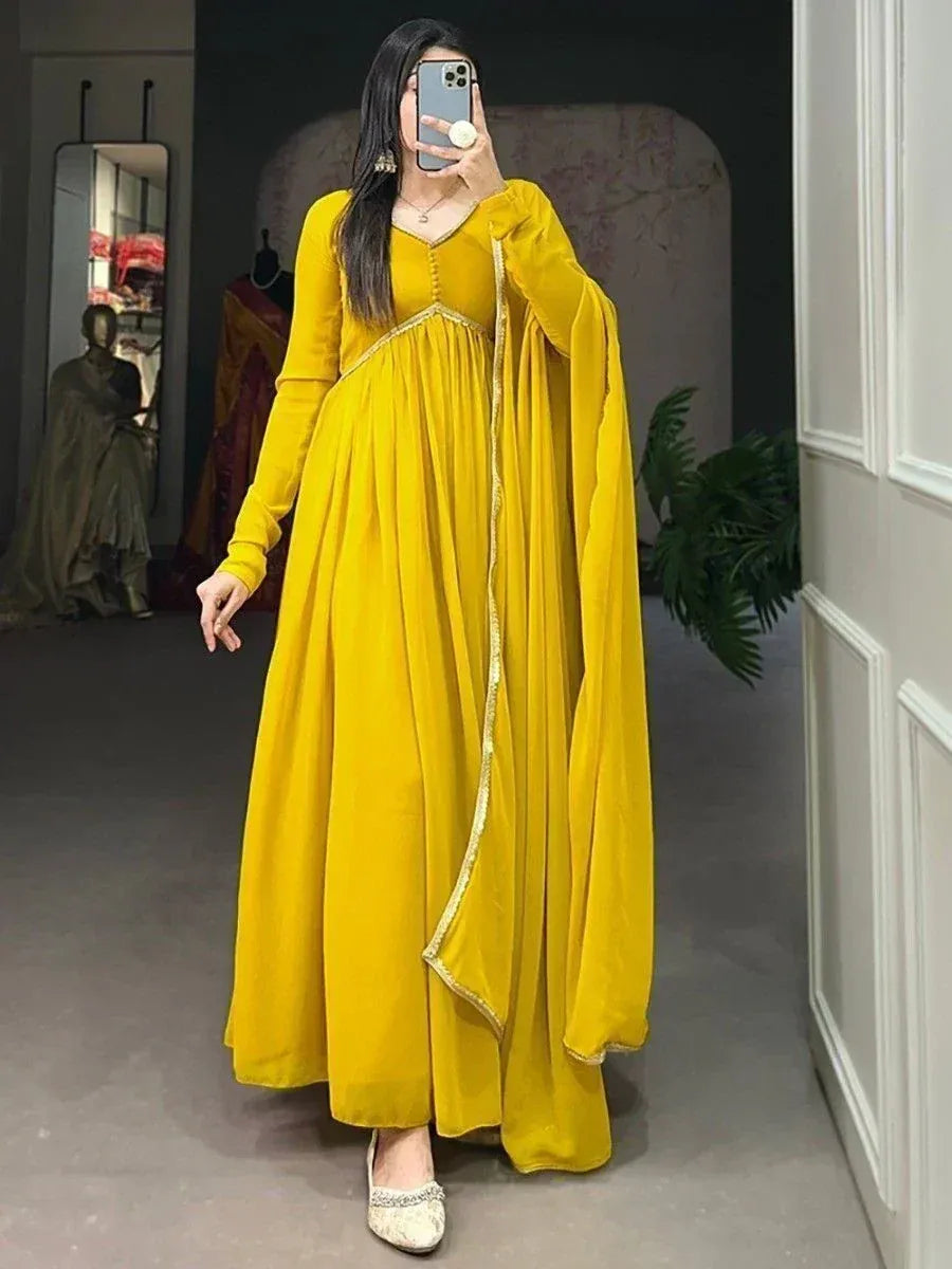 Vibrant yellow ethnic gown with gold trim, long sleeves, and flared skirt, perfect for Indian occasions